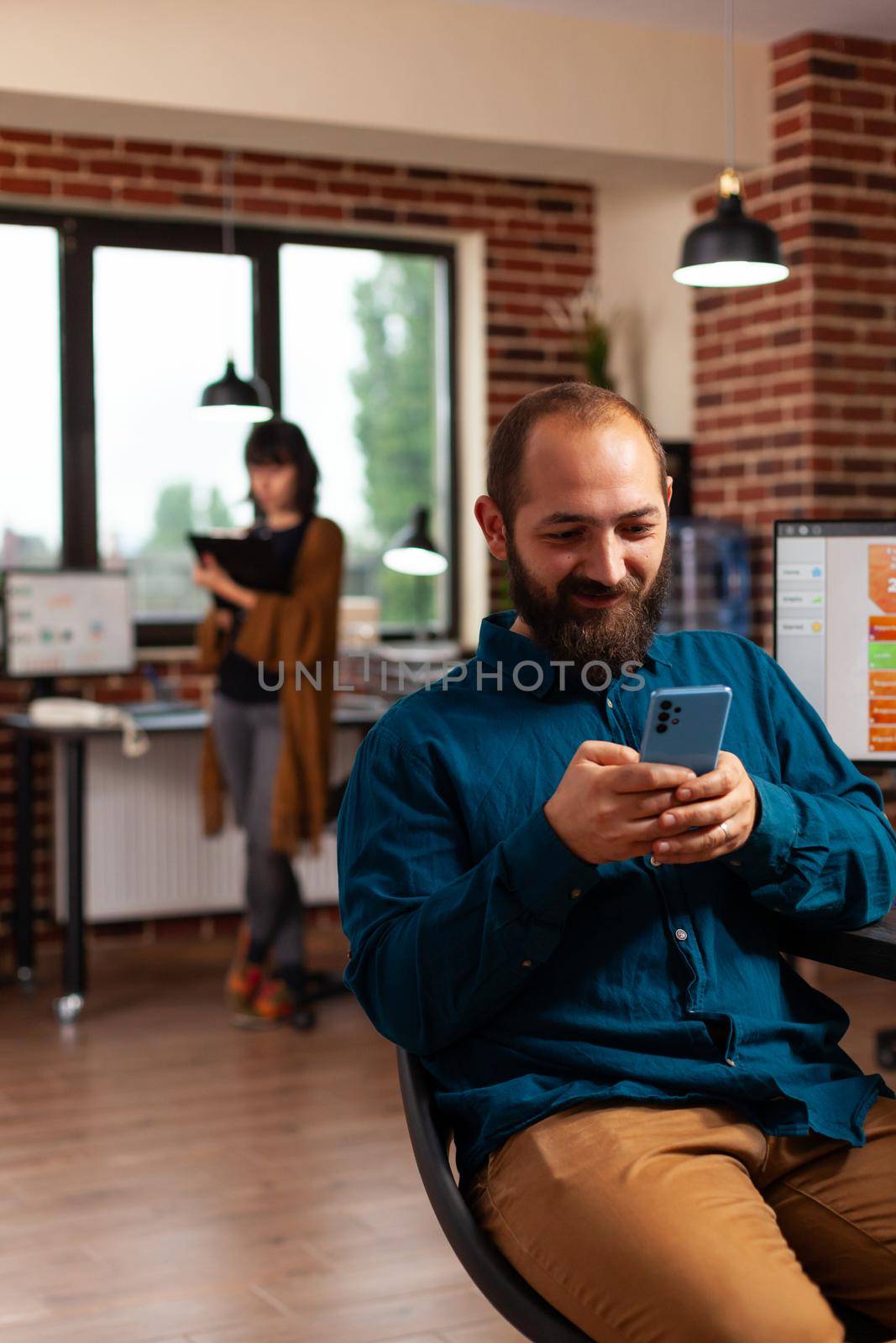 Businessman holding modern smartphone browsing on social media texting with remote friend by DCStudio