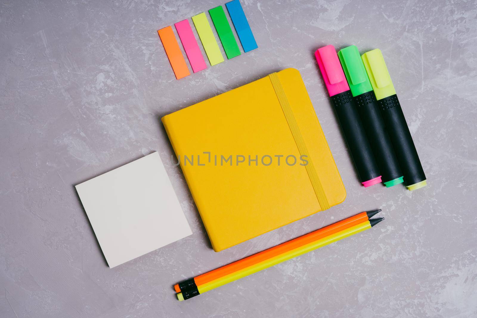 Stationery for schoolchildren and students. Back to school. Colored text makers, bookmarks, simple pencils, a yellow notepad on an elastic band and sheets for records.