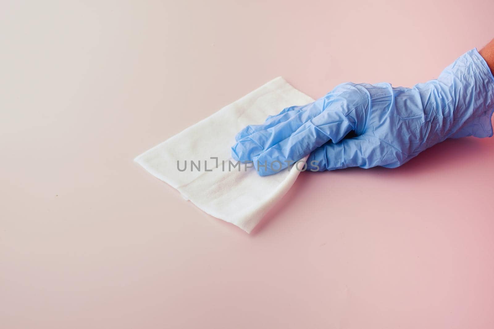 hand in blue rubber gloves cleaning table with towel .