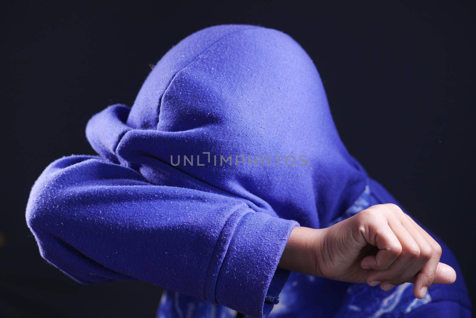 sad man in hood cover face with hands isolated in black