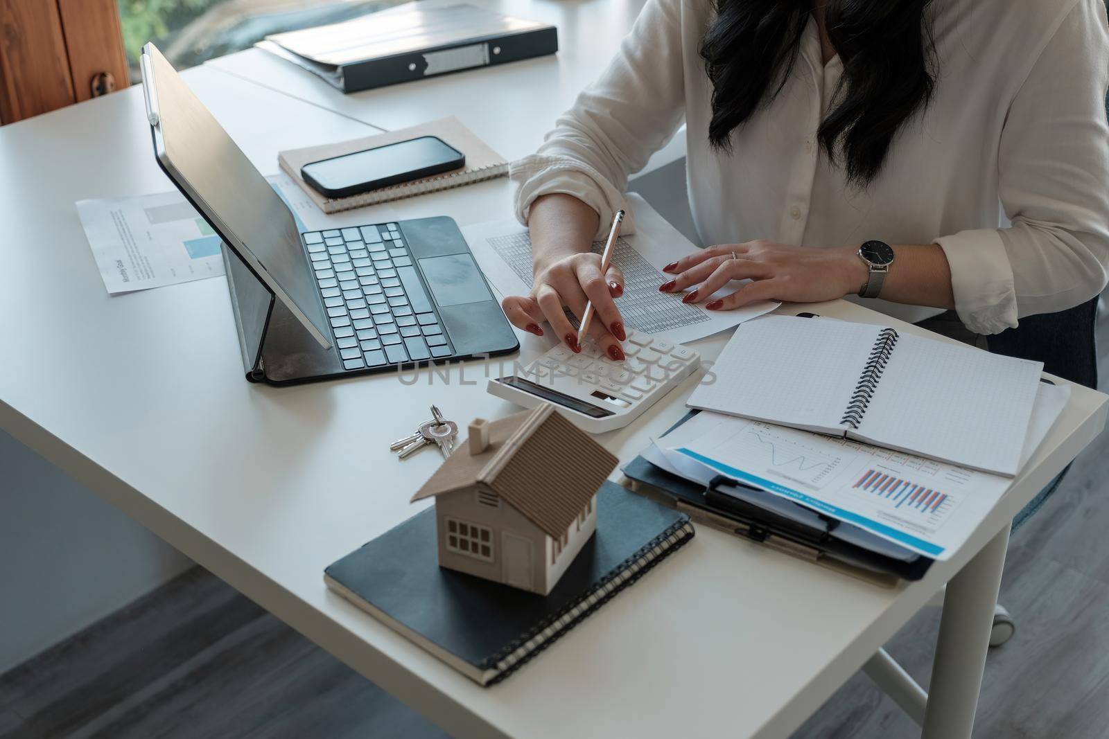 Close up hand of Business asian woman using calculating interest, taxes and profits to invest in real estate and home buying