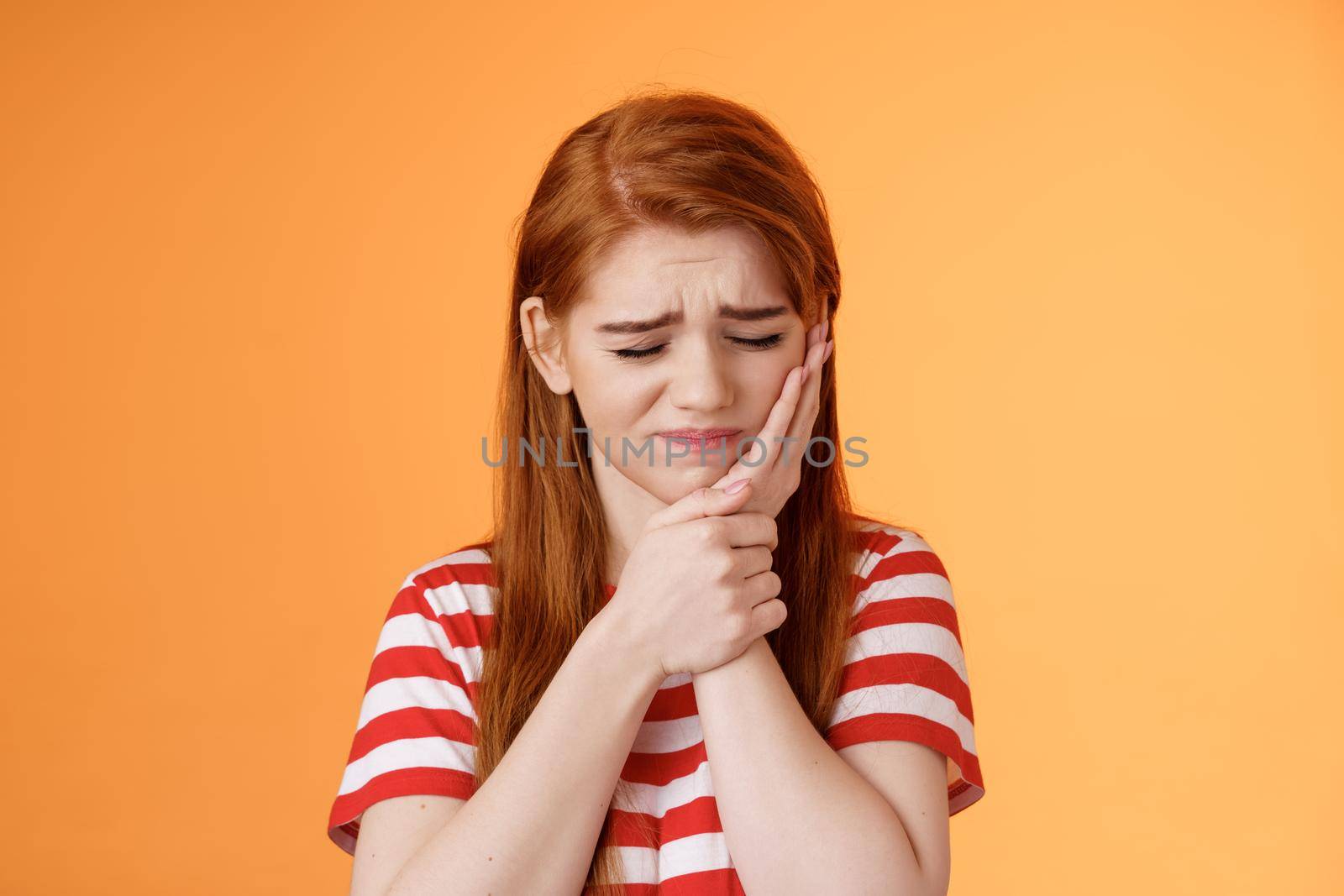 Close-up upset cute uneasy redhead girl suffer toothache, hold hand cheek frowning, close eyes awful tooth pain, have rotten teeth, decay problems, make dentist appointment, wait dental clinic.