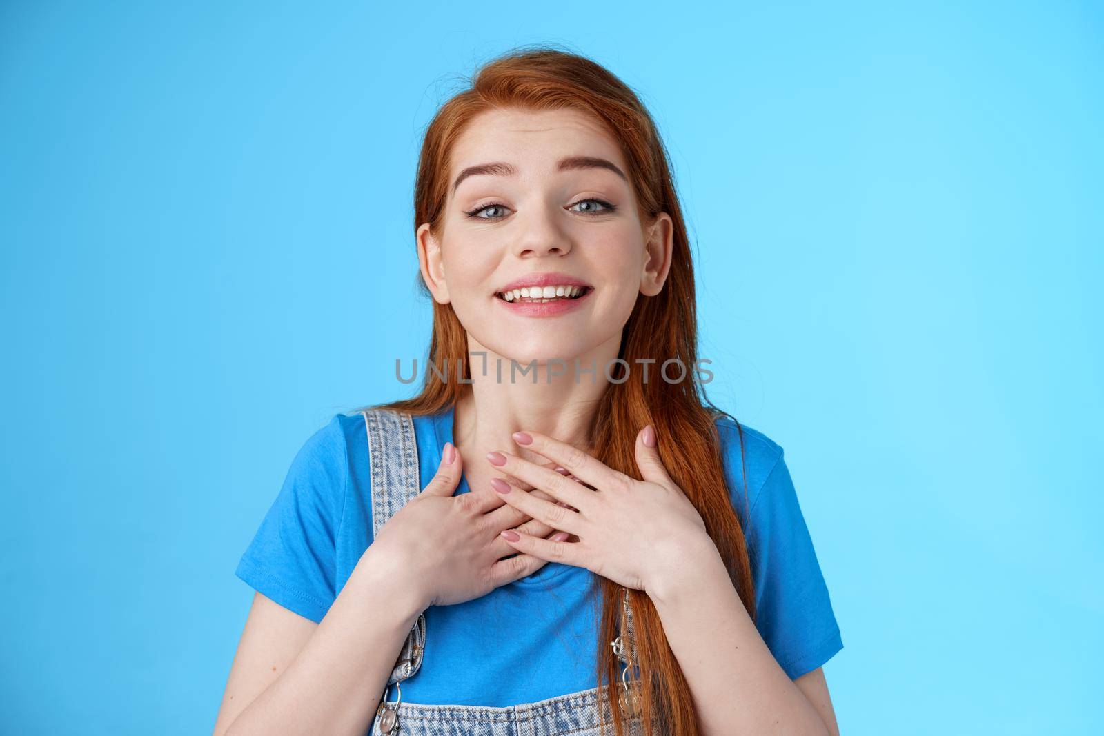 Grateful sincere cute charming redhead female thanking friends, smiling delighted appreciate nice tender gesture, press palms chest heart, grateful, look admiration and love, stand blue background.
