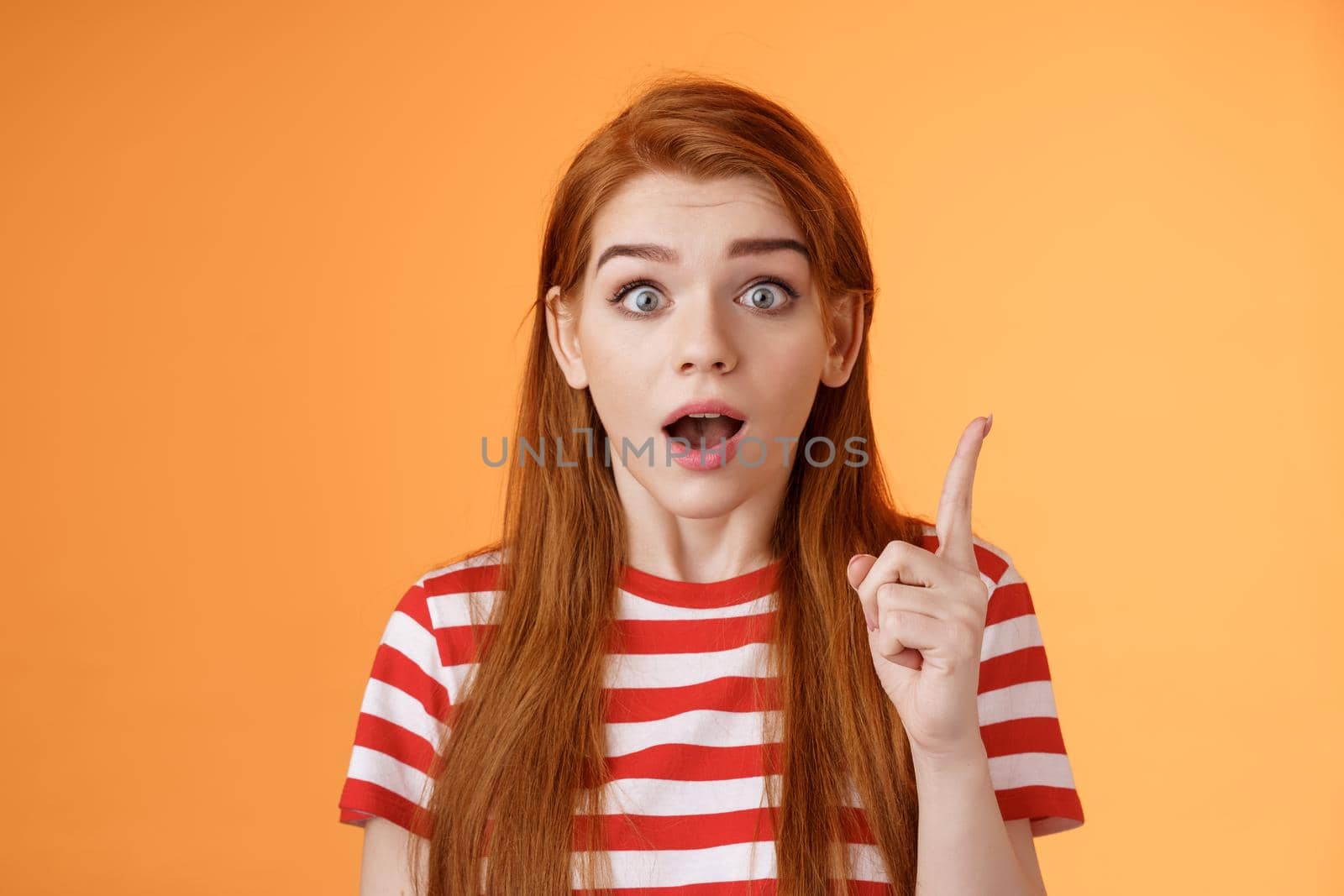 Got idea. Excited redhead woman sharing interesting plan, raise index finger eureka gesture, open mouth say thought, remember important thing, stare camera stunned, finally understand by Benzoix