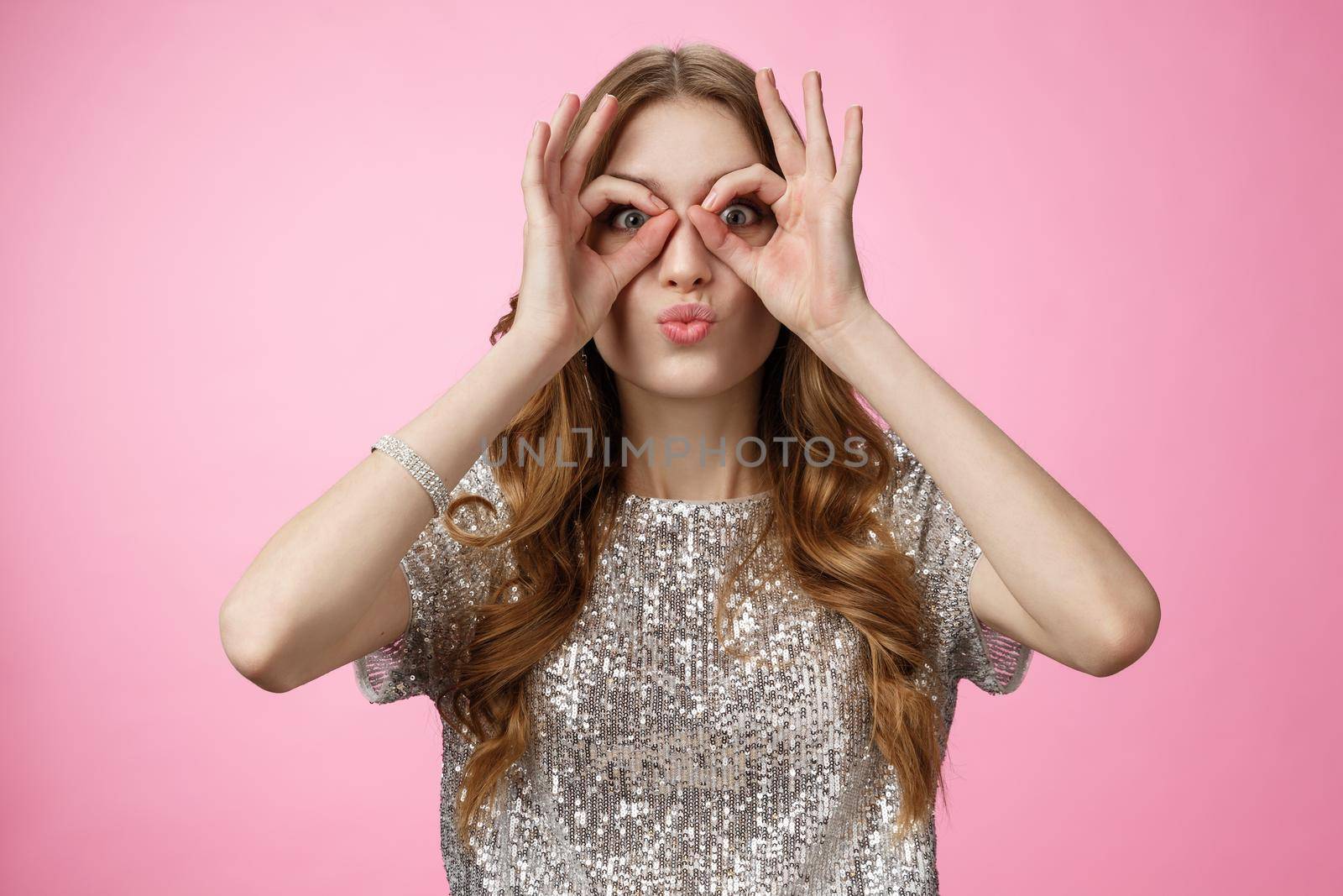 Funny cute attractive european young woman not afraid be immature playful folding lips silly show glasses make goggles using hands fooling around mimicking pilot, standing happy pink background by Benzoix