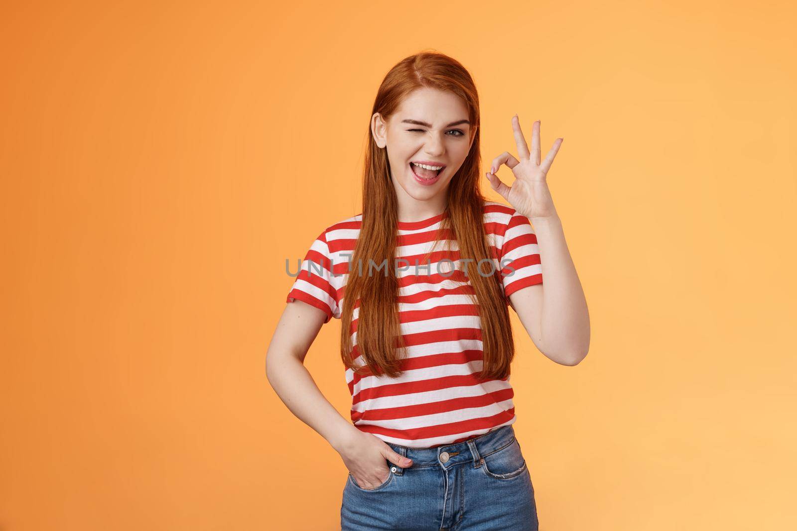 Sassy stylish sly redhead cheerful girl assuring everything excellent, show okay sign and wink cheeky, accept awesome idea, approve good job, express satifaction from positive result, like choice.