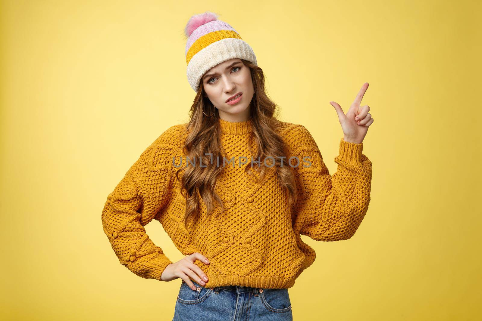 You call it advertisement, bad. Unimpressed displeased snobbish demanding female displeased hotel service pointing upper right corner cringing bothered frowning complaining yellow background.