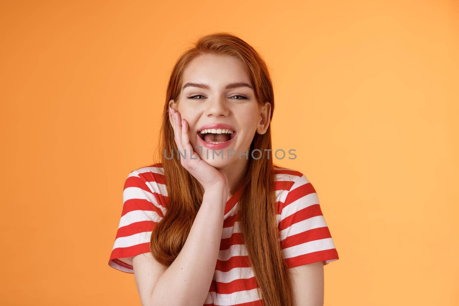 Cute cheerful smiling redhead woman talking friends, laughing out loud happily showing healthy toothy white smile, touch cheek silly, lovely giggling funny conversation, happy orange background by Benzoix