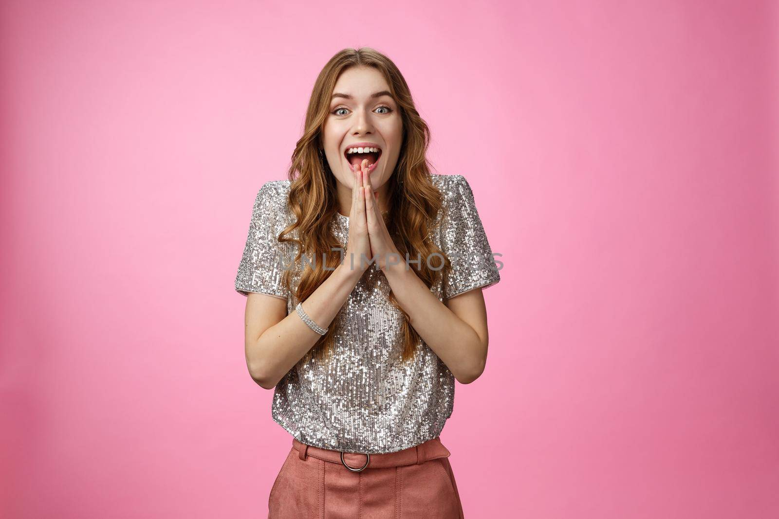 Excited attractive girlfriend eager start pack ready travel abroad win tickets press palms together happily thrilled looking amused feeling happiness standing pink background glamour outfit.