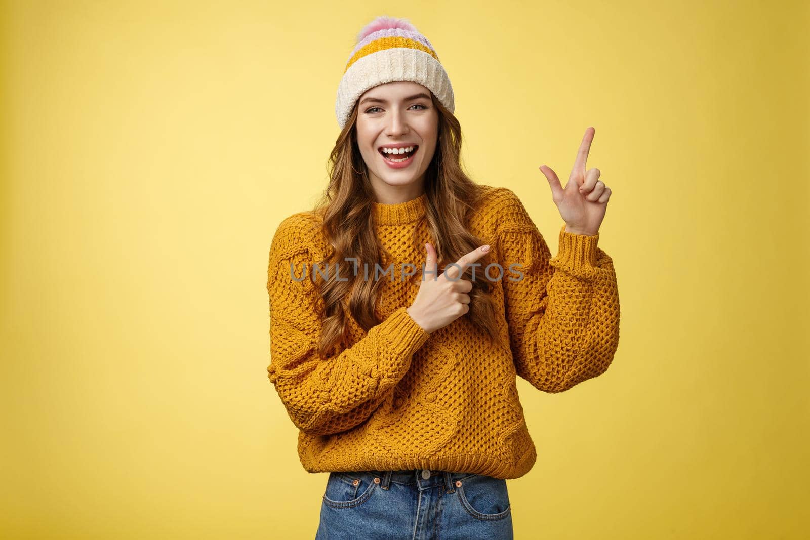 Carefree friendly nice flirty stylish woman wearing sweater hat laughing joyfully enjoying funny company joking pointing upper right corner index fingers delighted, showing cool promotion.