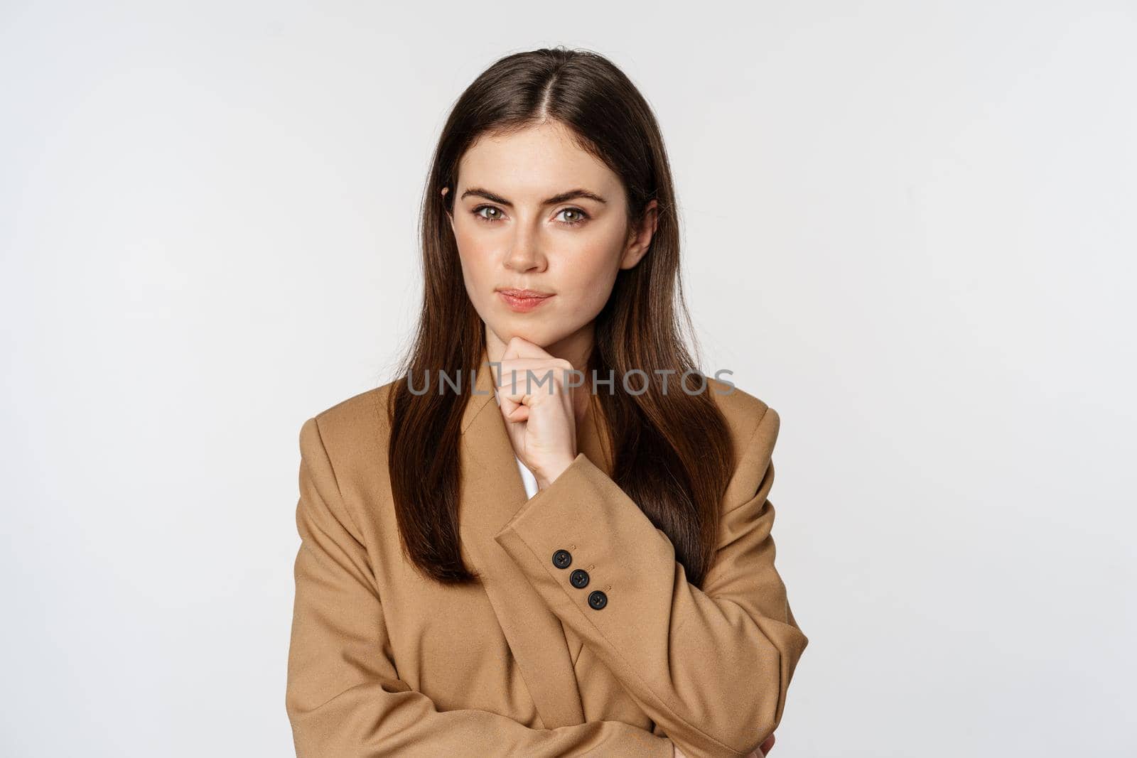 Image of businesswoman thinking, corporate woman looking thoughtful, making decision, standing in brown suit over white background.