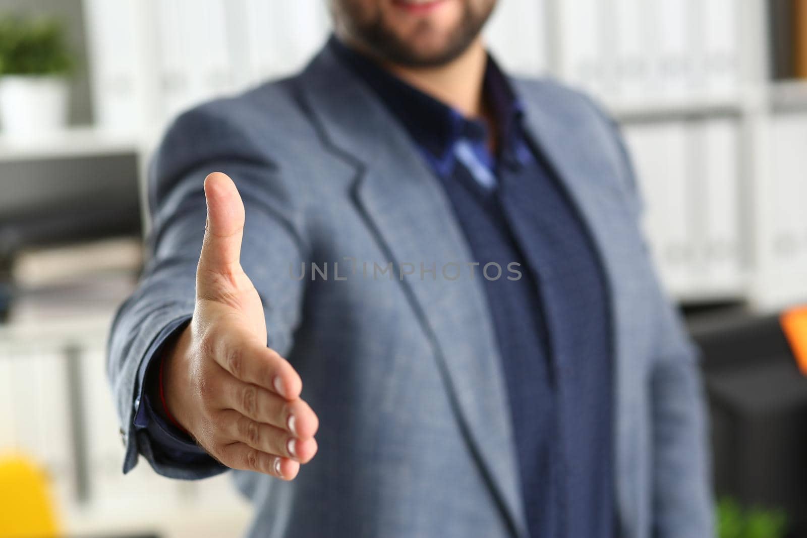 Businessman working in the office, reaching out hand forward for handshake. Business arrangement concept