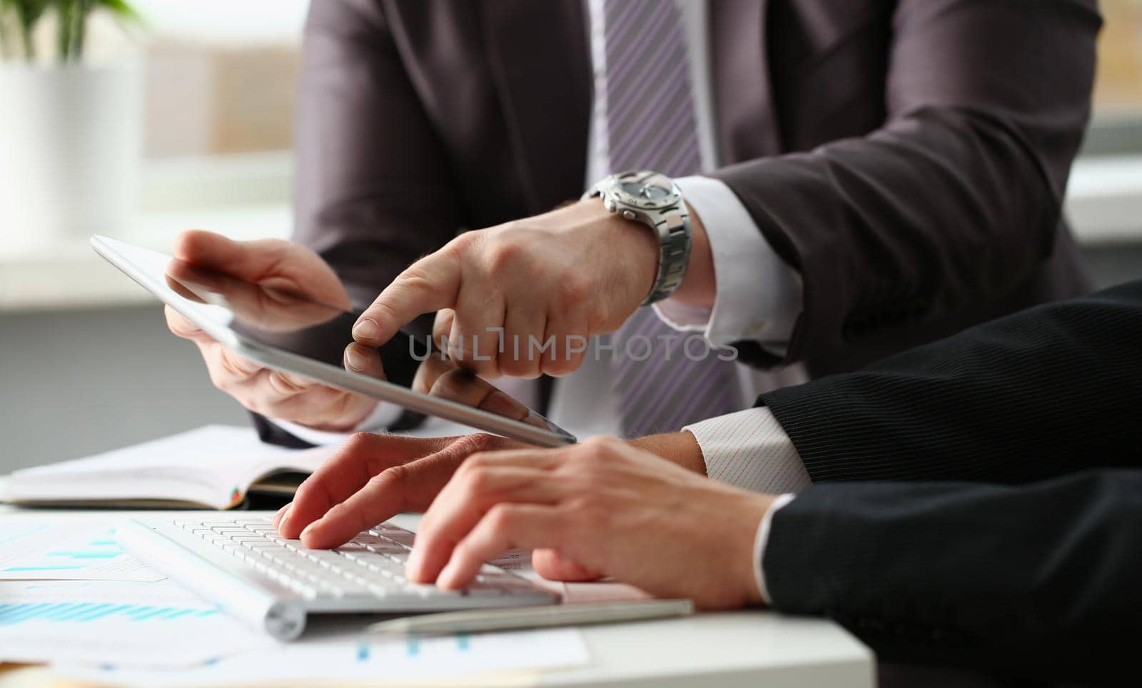 Two businessmen are looking and studying business statistics on tablet display. Mobile business applications for business concept