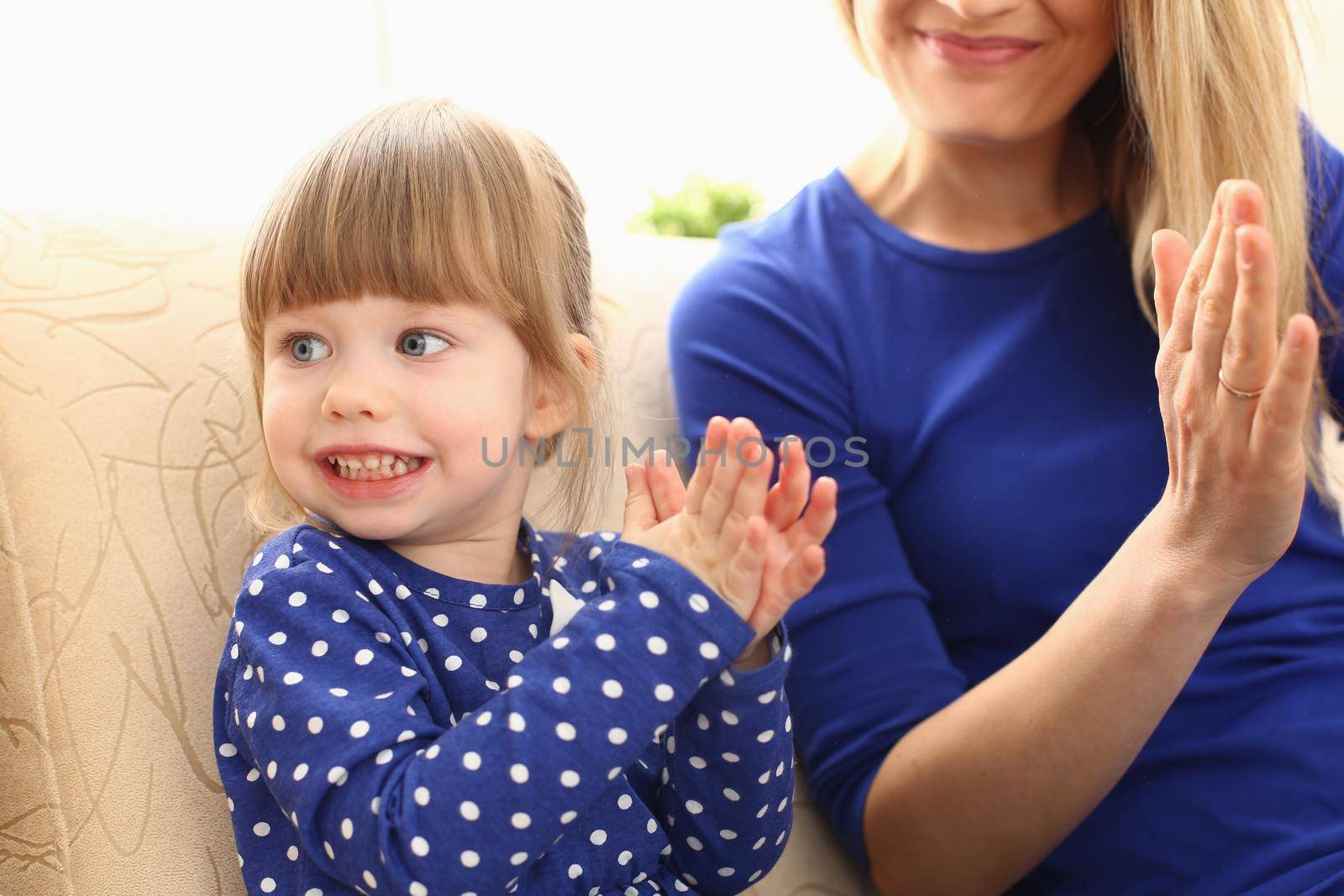 Cute little girl plays with mom and claps hands. Home games with young children concept