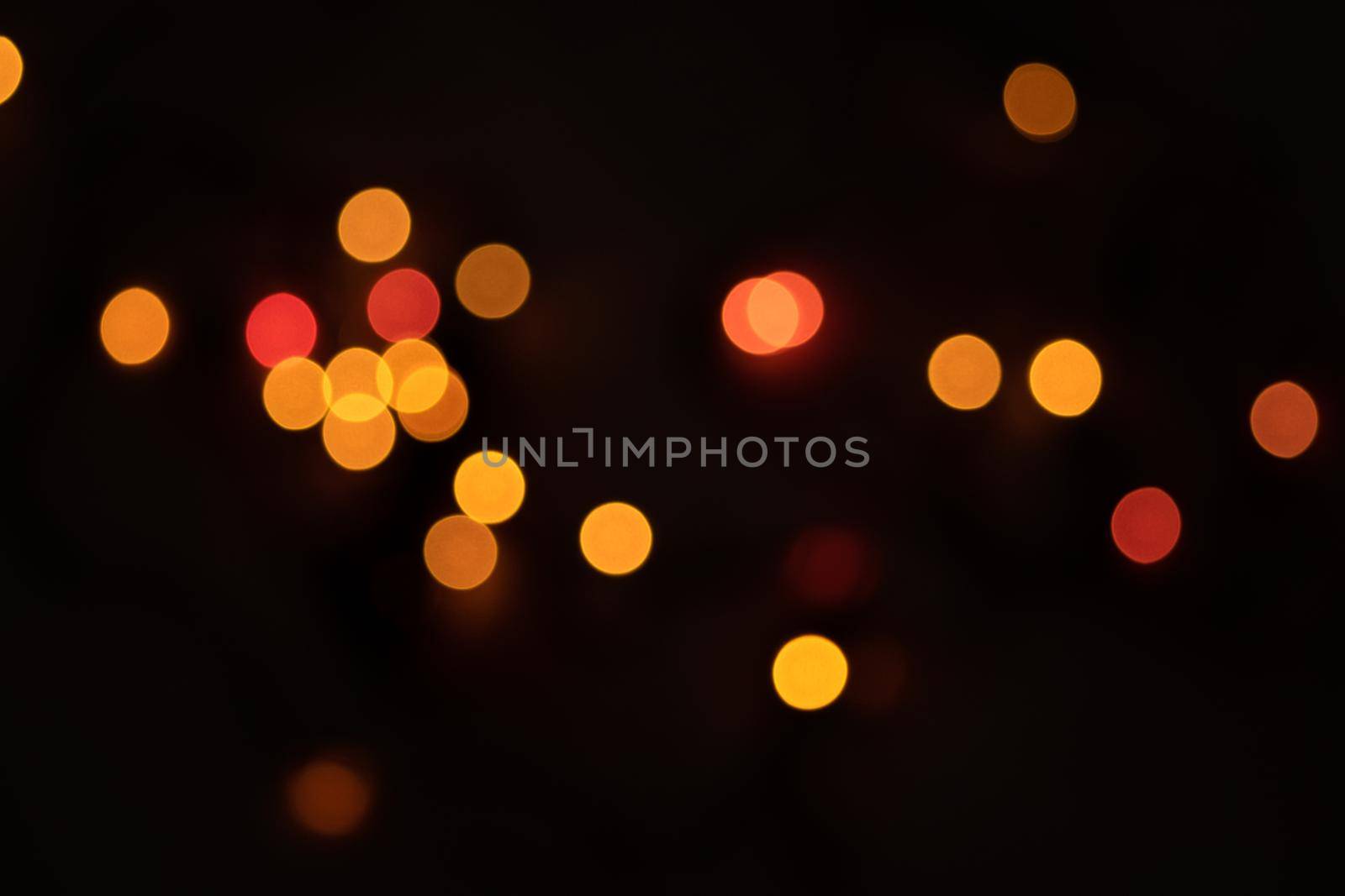 Defocused bokeh lights on black background, an abstract naturally blurred backdrop for Valentine's Day or birthday party. Festive light texture. Pink and red garland in blur. Overlay effect for design