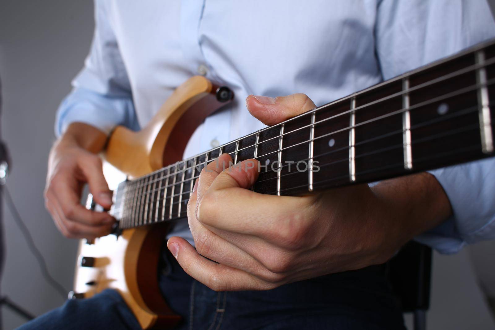 Male hands are playing a wooden six mstring guitar. Guitar learning concept