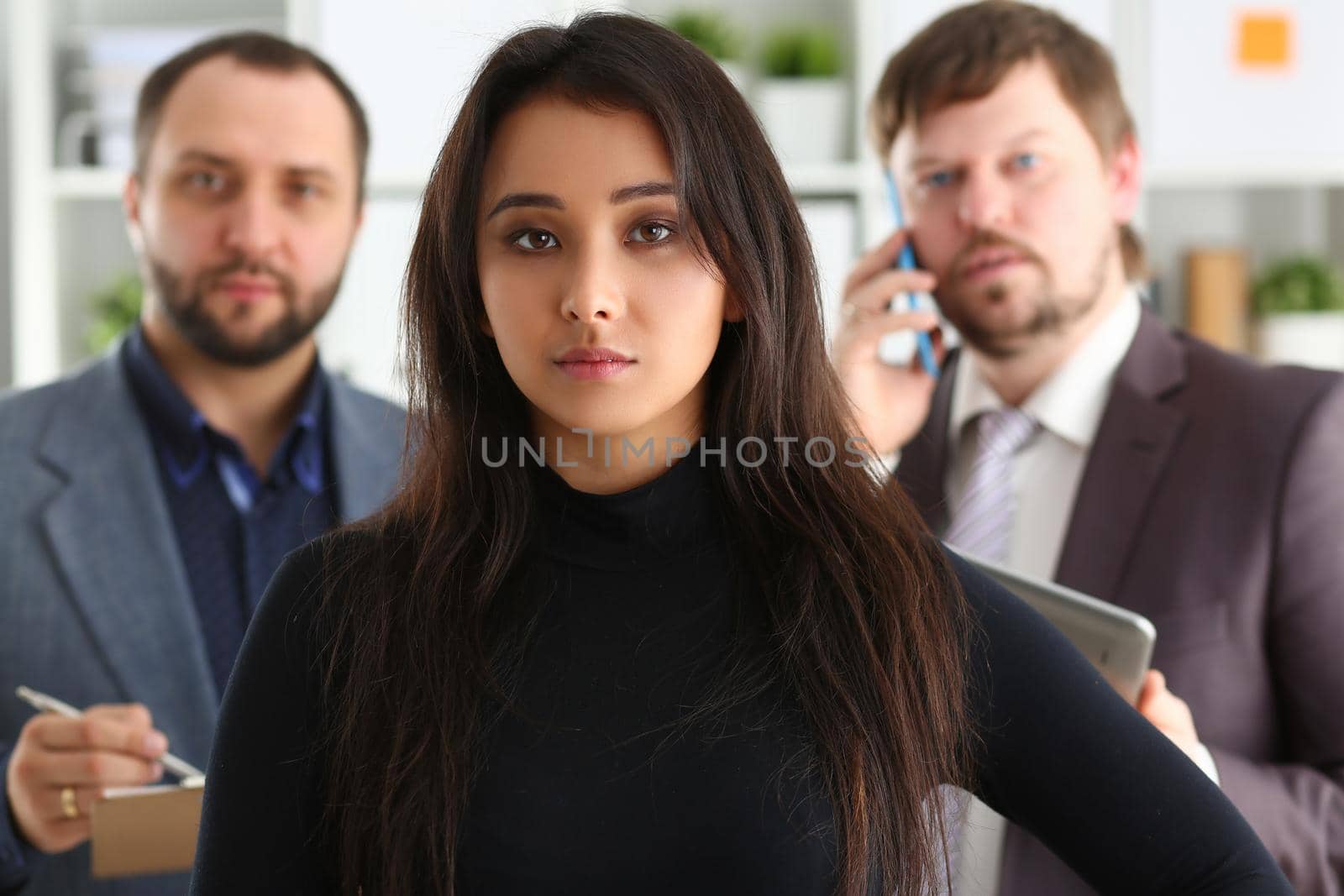 Portrait of young successful business woman and two businessmen in office. Successful collaboration concept