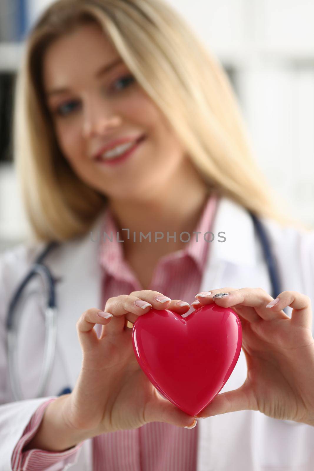 Cardiologist holds red heart in hands. Types of diseases of cardiovascular system concept