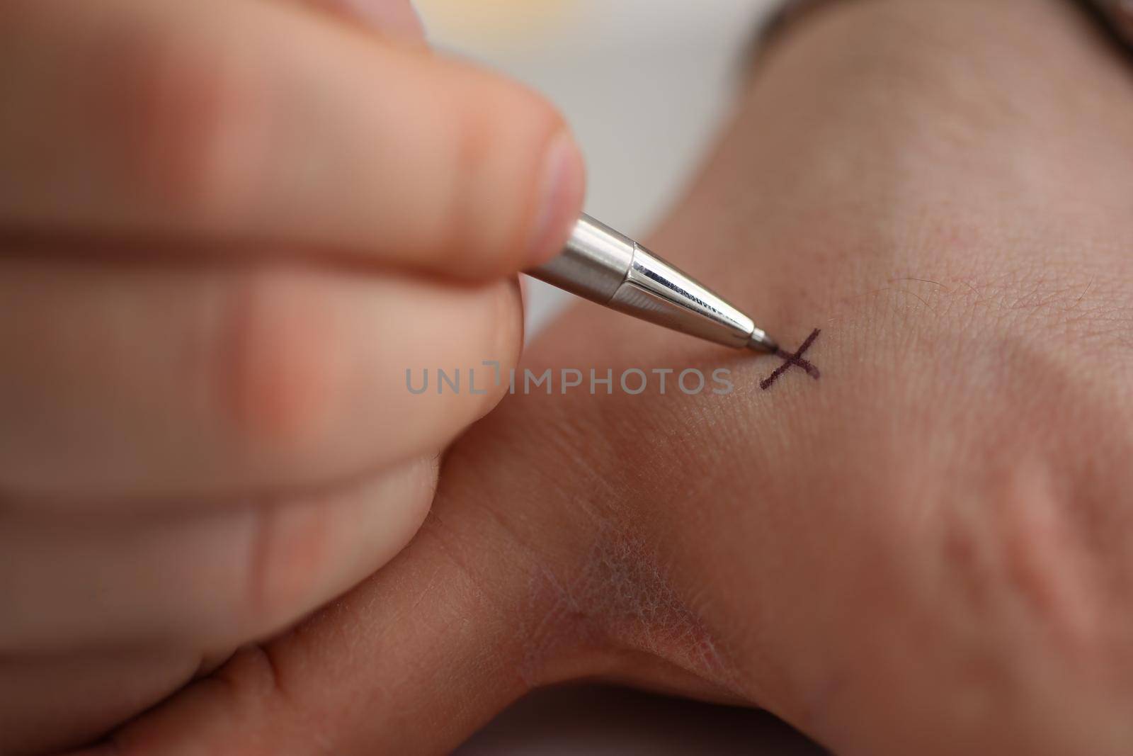 Man makes x note with cross with pen on hand, closeup. Try not to forget to do list concept