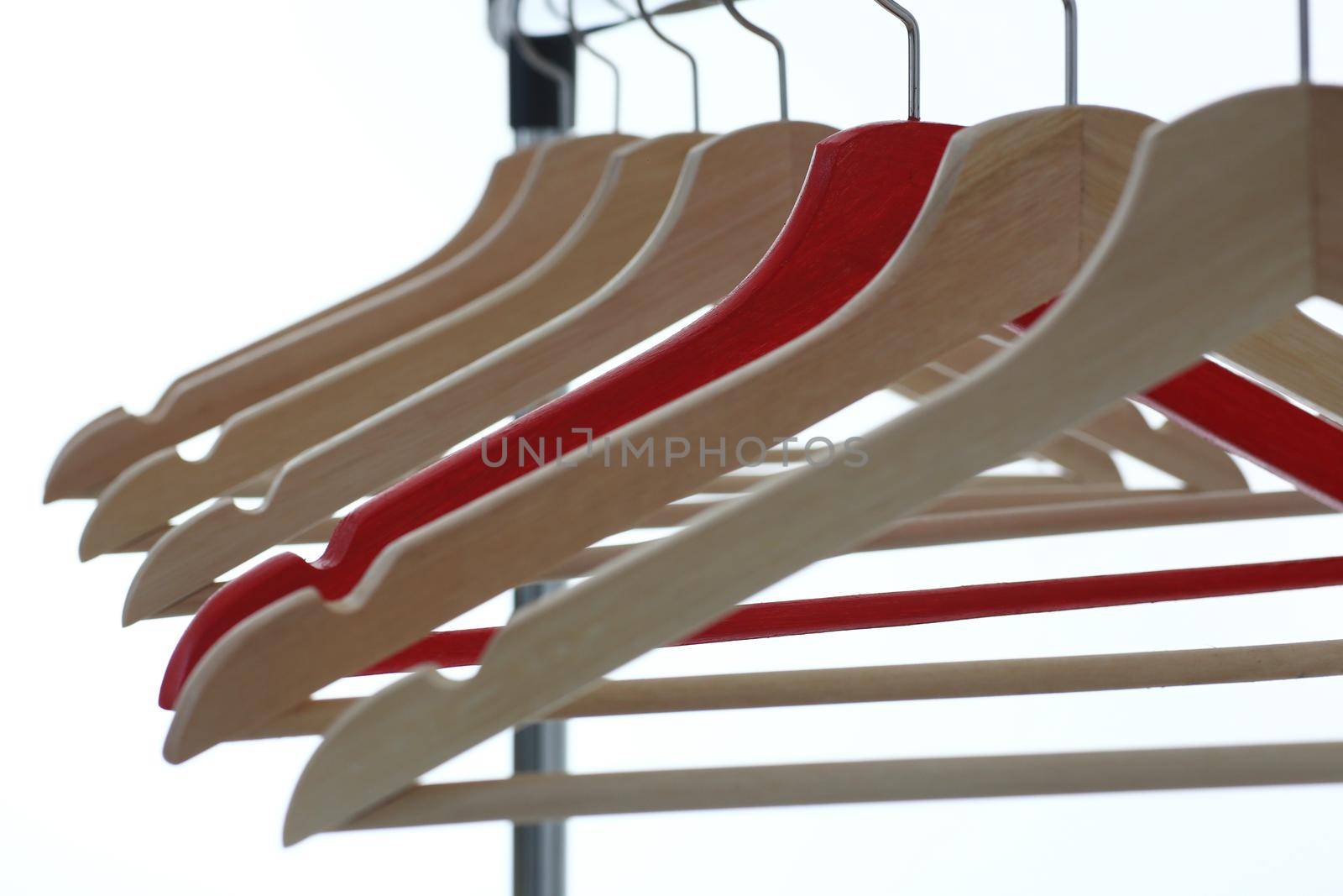 Red and wooden hanger hanging from metal pipe. Business leader selling clothes and style concept