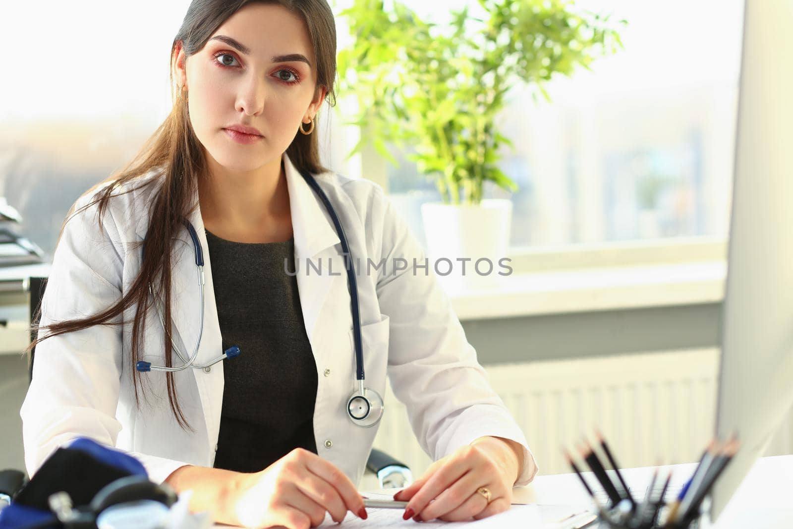 Woman doctor in medical gown at workplace. Disease prevention and patient examination concept