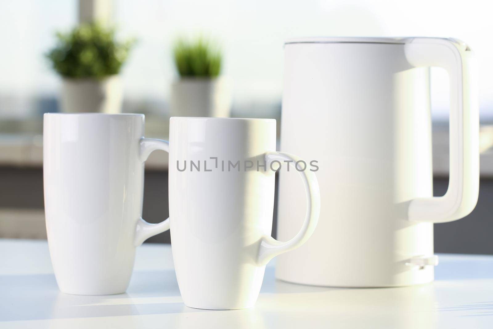 Teapot and two trendy cups are on the table for evening family tea. Stylish kitchen utensils concept