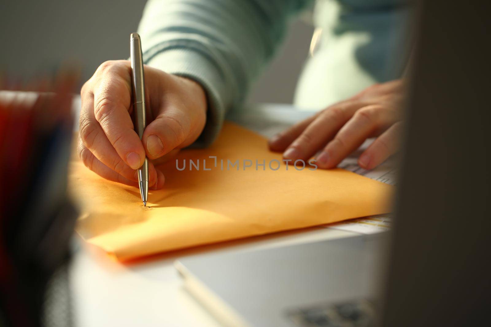 Male hand fills out the address on yellow postage envelope. Delivery and dispatch of mail concept