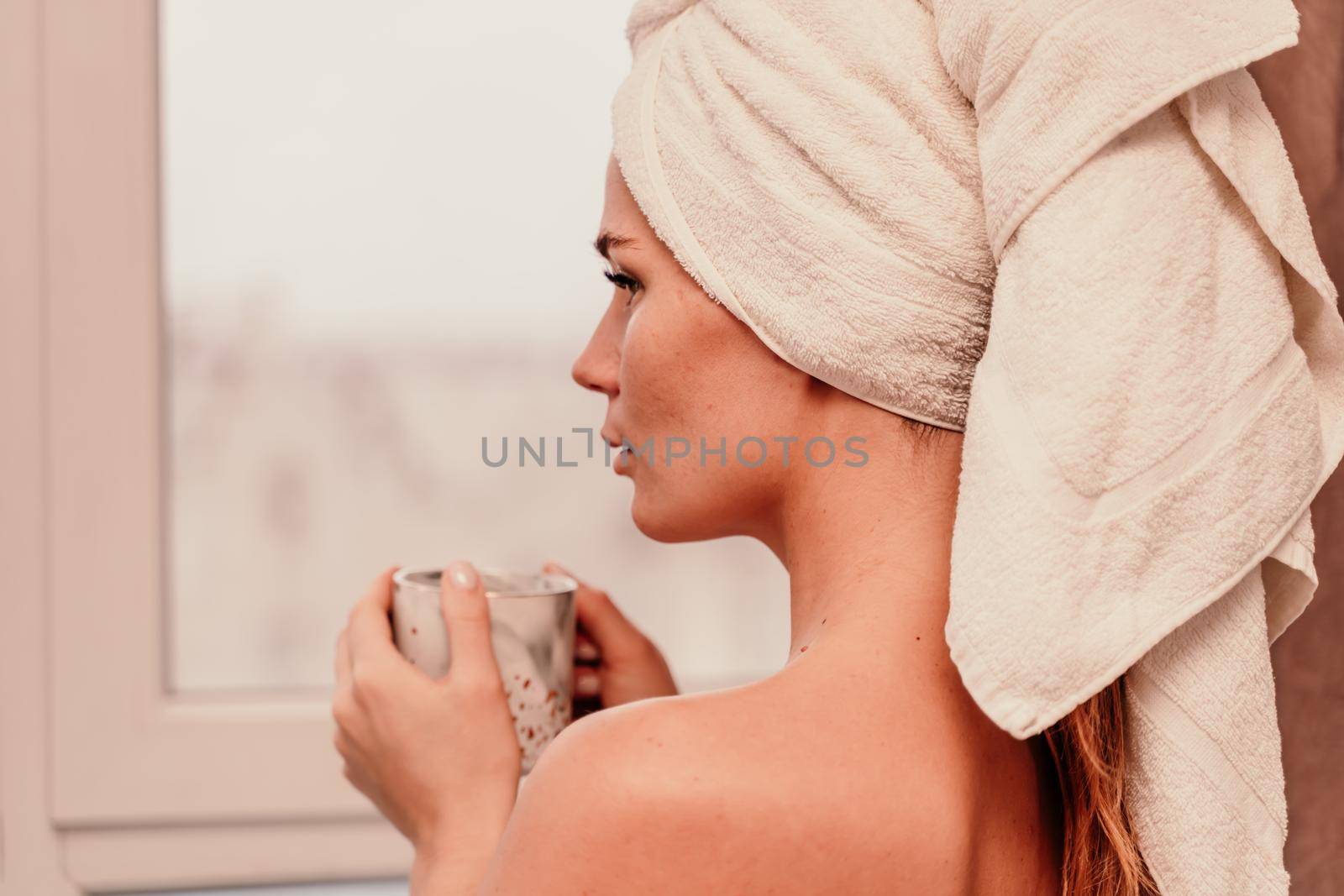 Young serene relaxed woman in spa bath towel drinking hot beverage tea coffee after taking shower bath at home. Beauty treatment, hydration concept by Matiunina