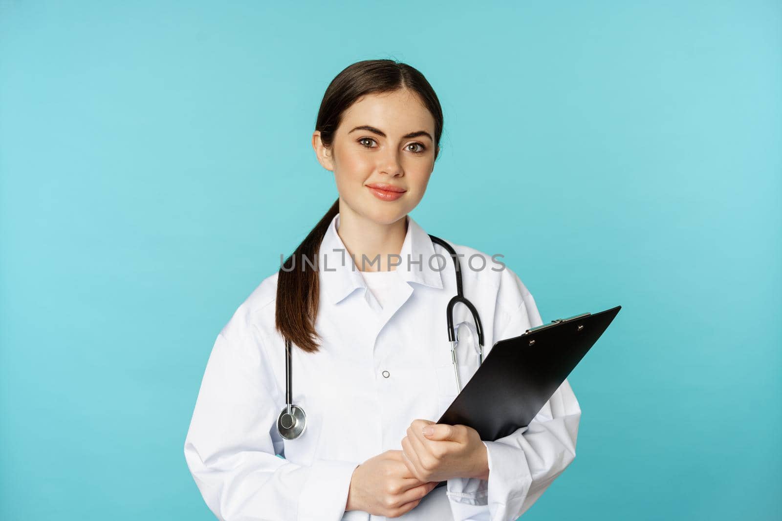 Image of professional woman doctor, physician with clipboard writing, listening patient at hospital clinic appointment, standing over torquoise background.