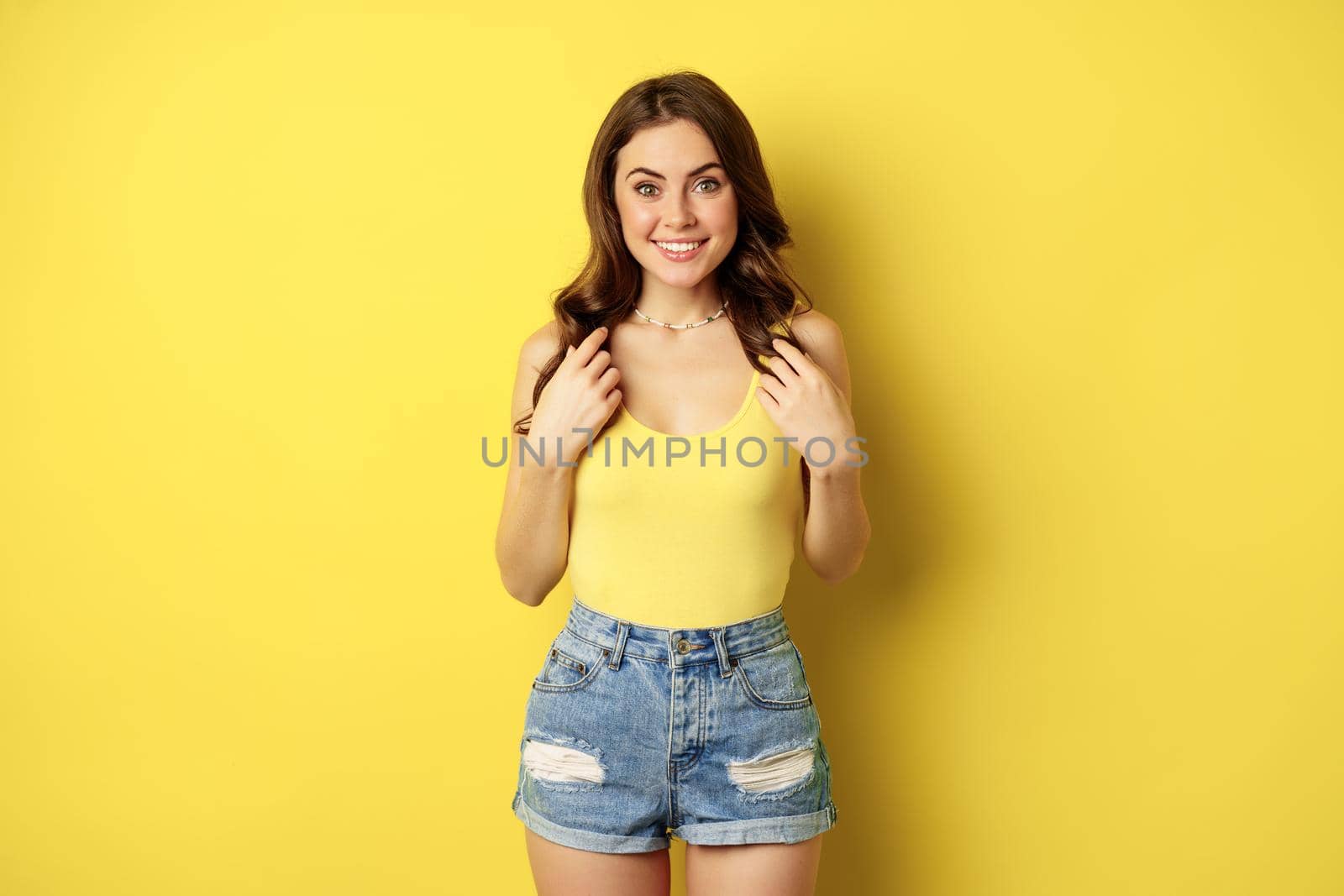 Portrait of enthusiastic, hopeful woman looking with yearning, smiling happy face, expecting smth, desire, standing over yellow background.