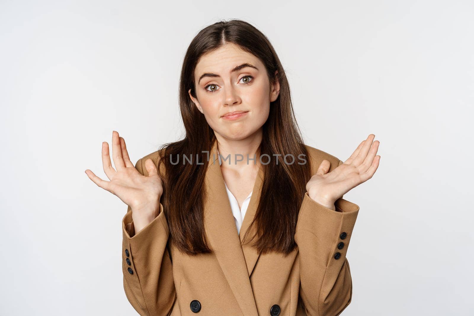 Portrait of corporate woman, office girl shrugging shoulders and looking clueless, dont know, puzzled, standing over white background.