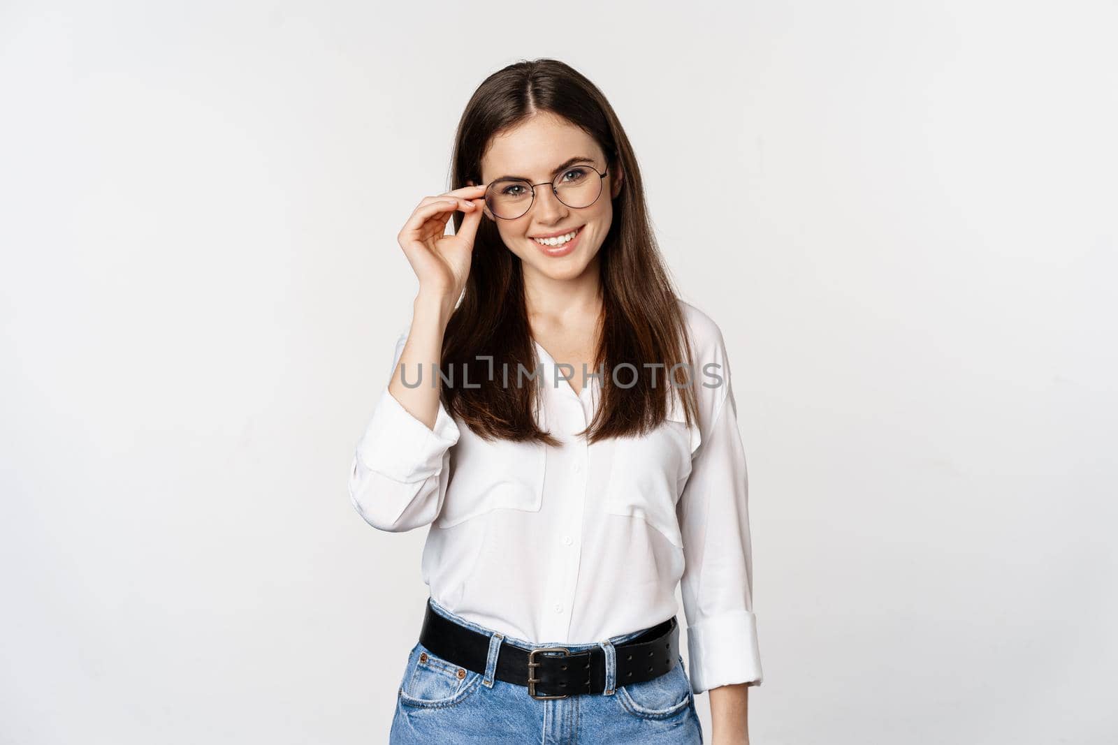 Portrait of female office worker, businesswoman looking at camera and smiling, standing over white background. Copy space