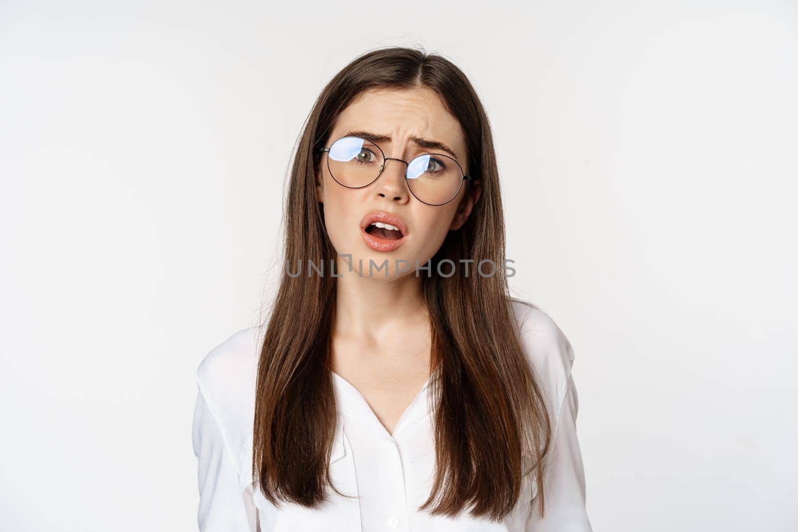 Close up of confused brunette woman in glasses, looking puzzled and clueless, standing over white background. Copy space