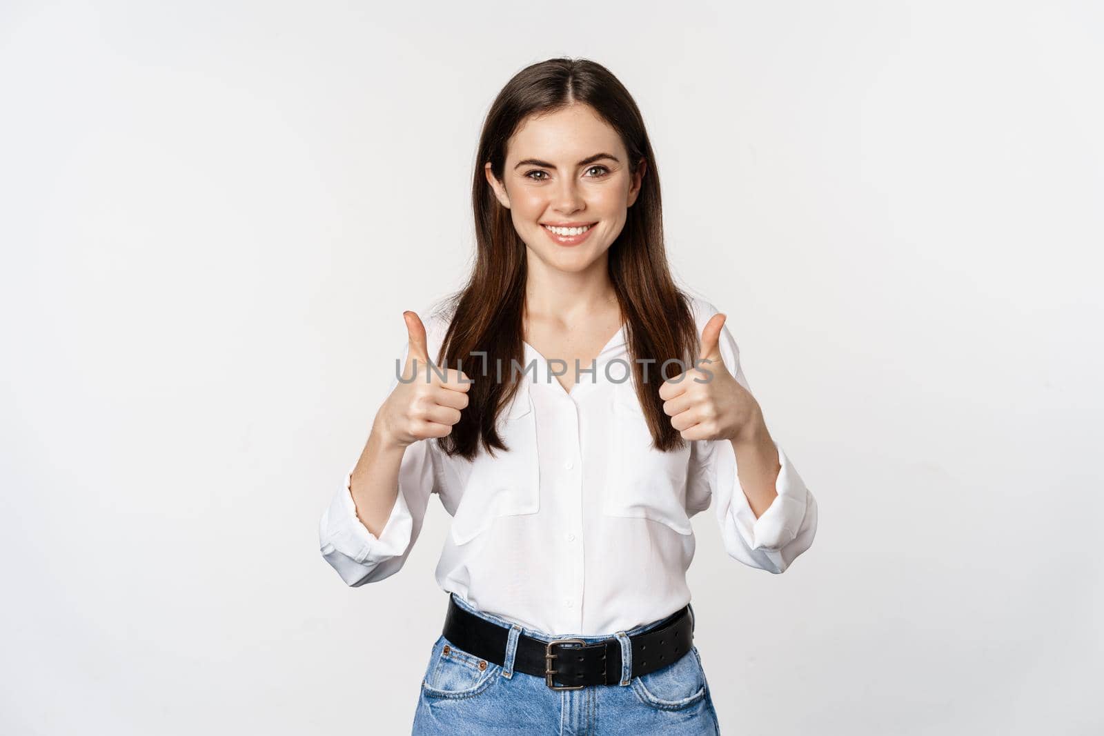 Happy smiling girl showing thumbs up, student with satisfied feedback, recommending smth, standing over white background.