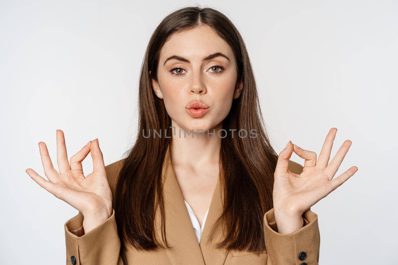 Mindfulness and meditation. Young businesswoman meditating, practice yoga, breathing calm and relaxed, standing over white background.