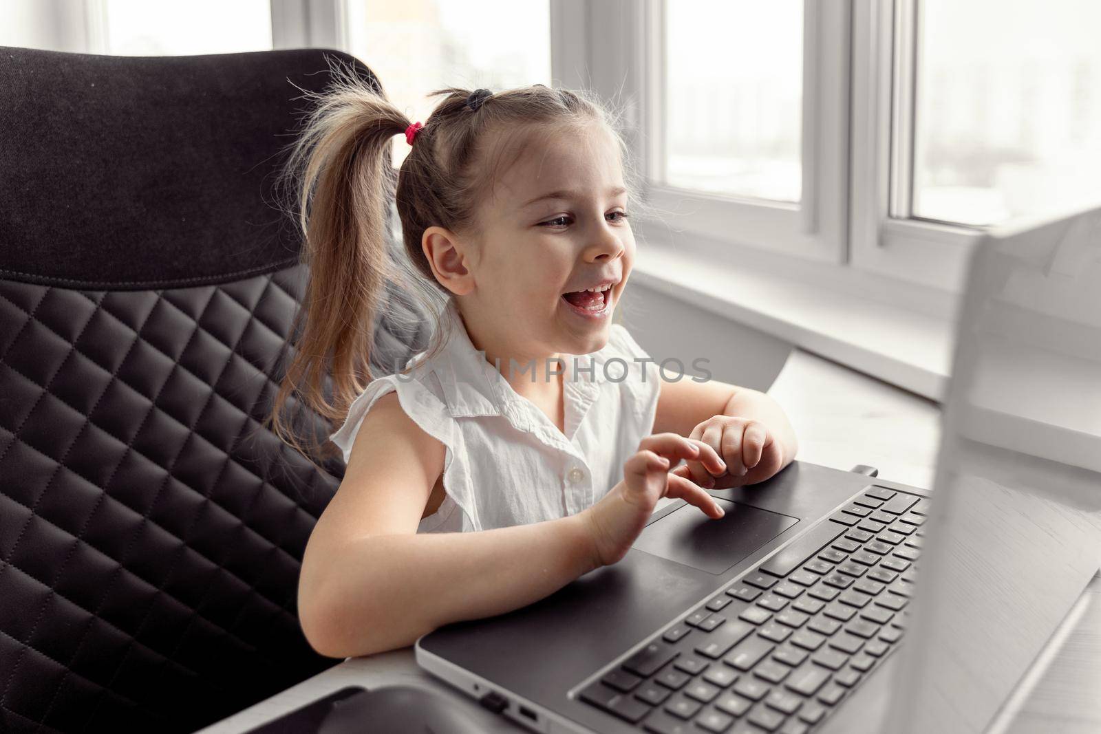 cute little caucasian girl studying online at home. children video conference with teacher tutor at home
