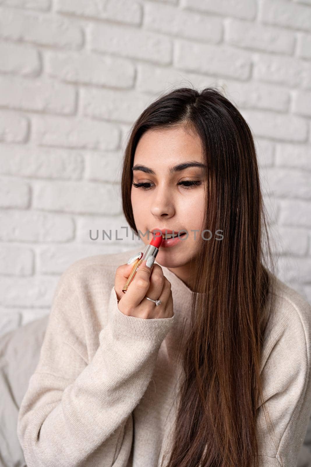 Valentine's day, Women's day. Brunette young caucasian Woman sitting on the bed making up coloring lips