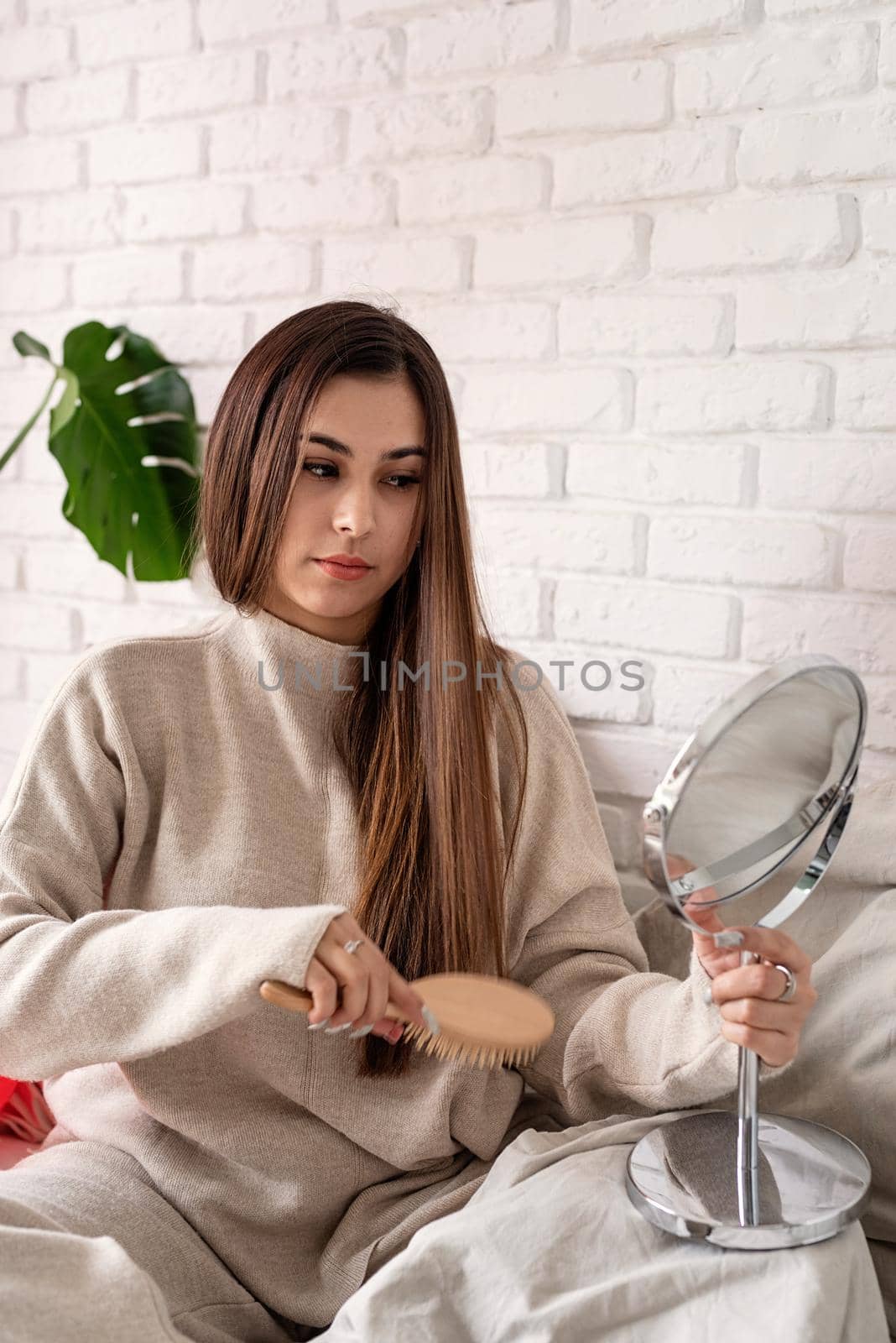 Valentine's day, Women's day. Brunette young Woman celebrating valentines day, sitting on the bed brushing hair looking at the mirror