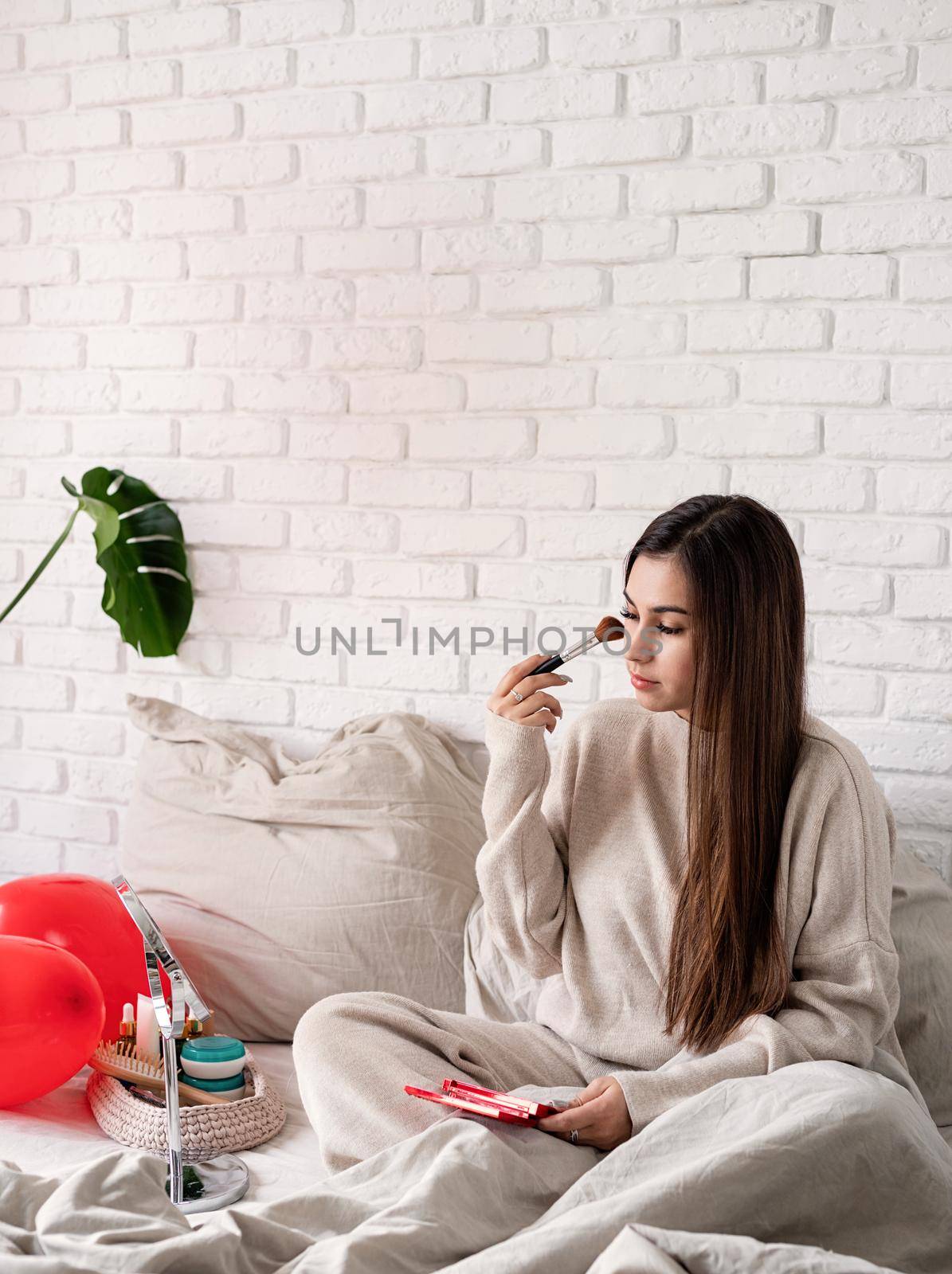 Woman celebrating valentines day, sitting on the bed making up by Desperada