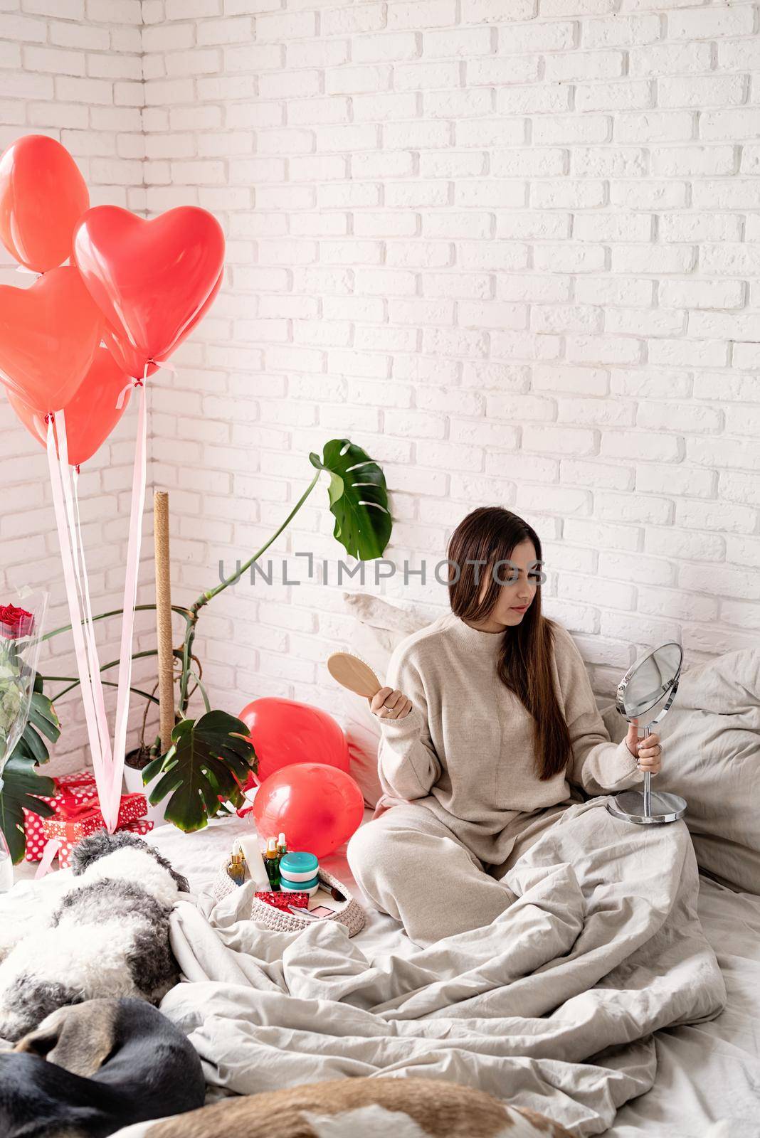 Valentine's day, Women's day. Brunette young Woman celebrating valentines day, sitting on the bed making up