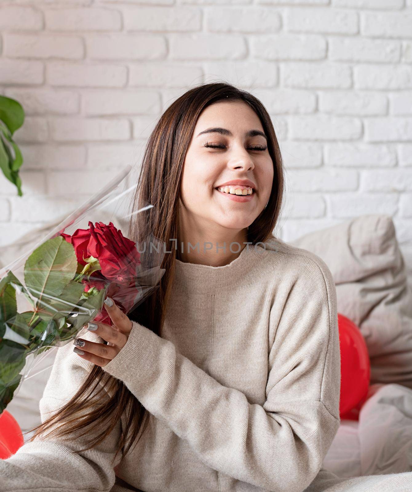 Young beautiful woman sitting in the bed celebrating valentine day holding red roses by Desperada