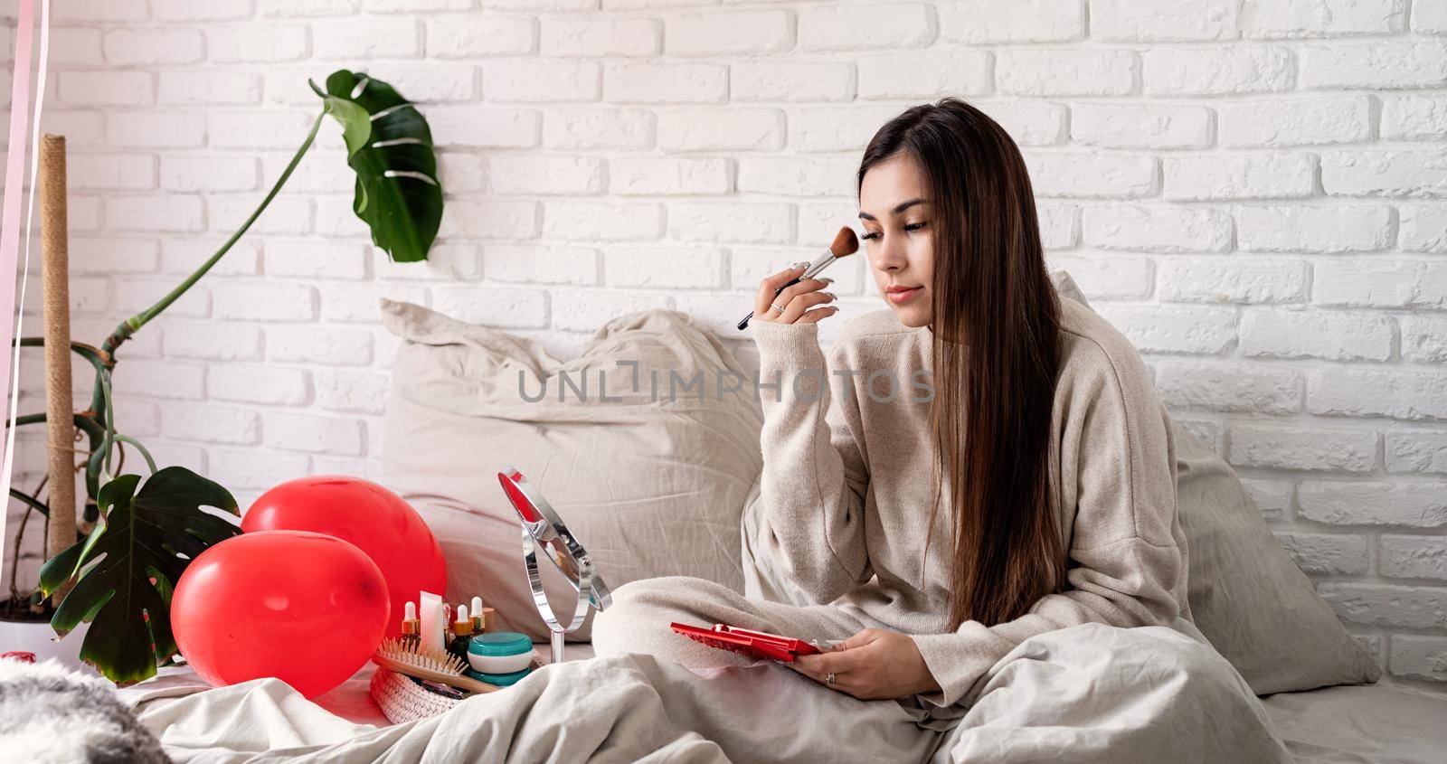 Valentine's day, Women's day. Brunette young Woman celebrating valentines day, sitting on the bed making up