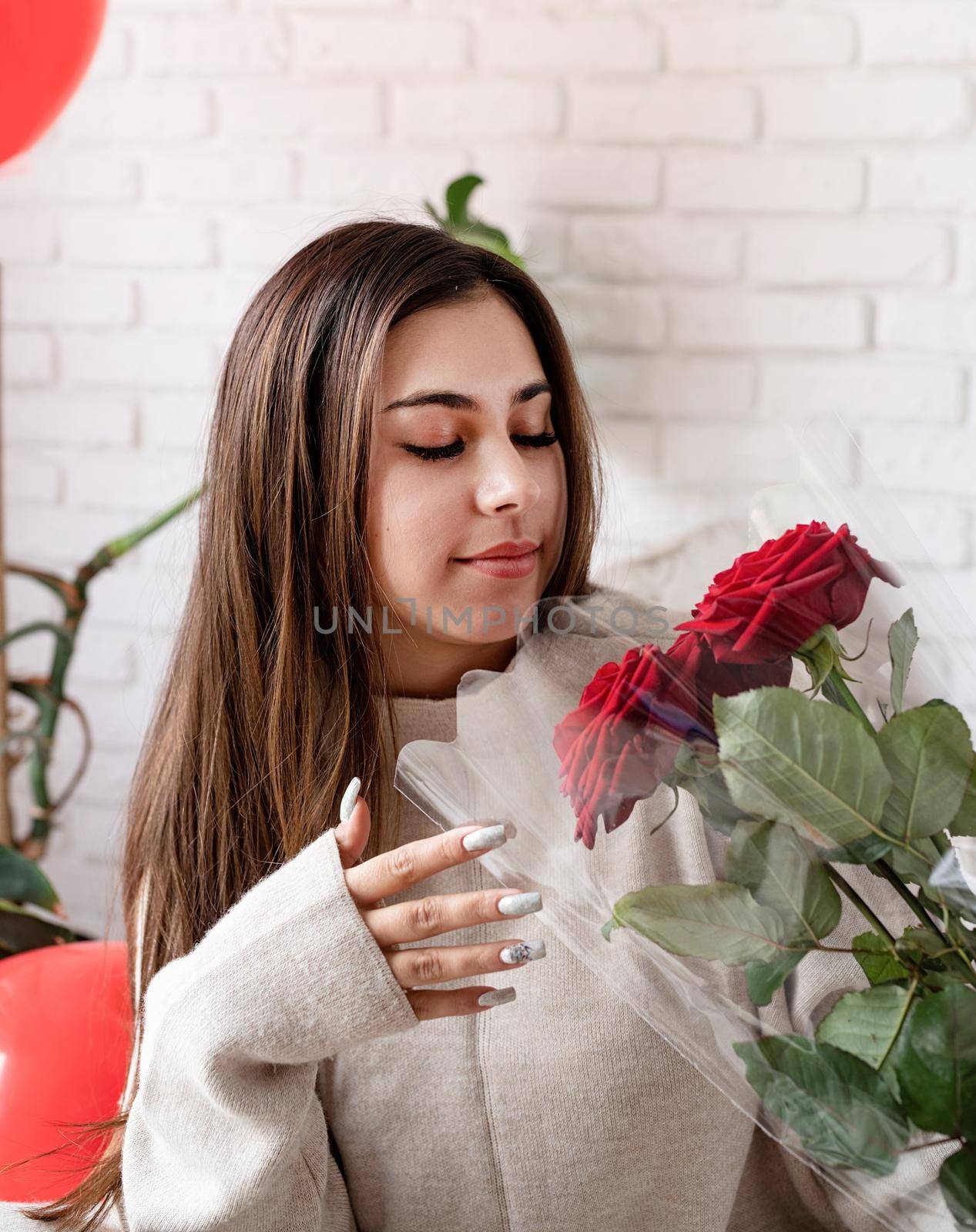 Happy laughing beautiful woman sitting in the bed celebrating valentine day holding red roses by Desperada