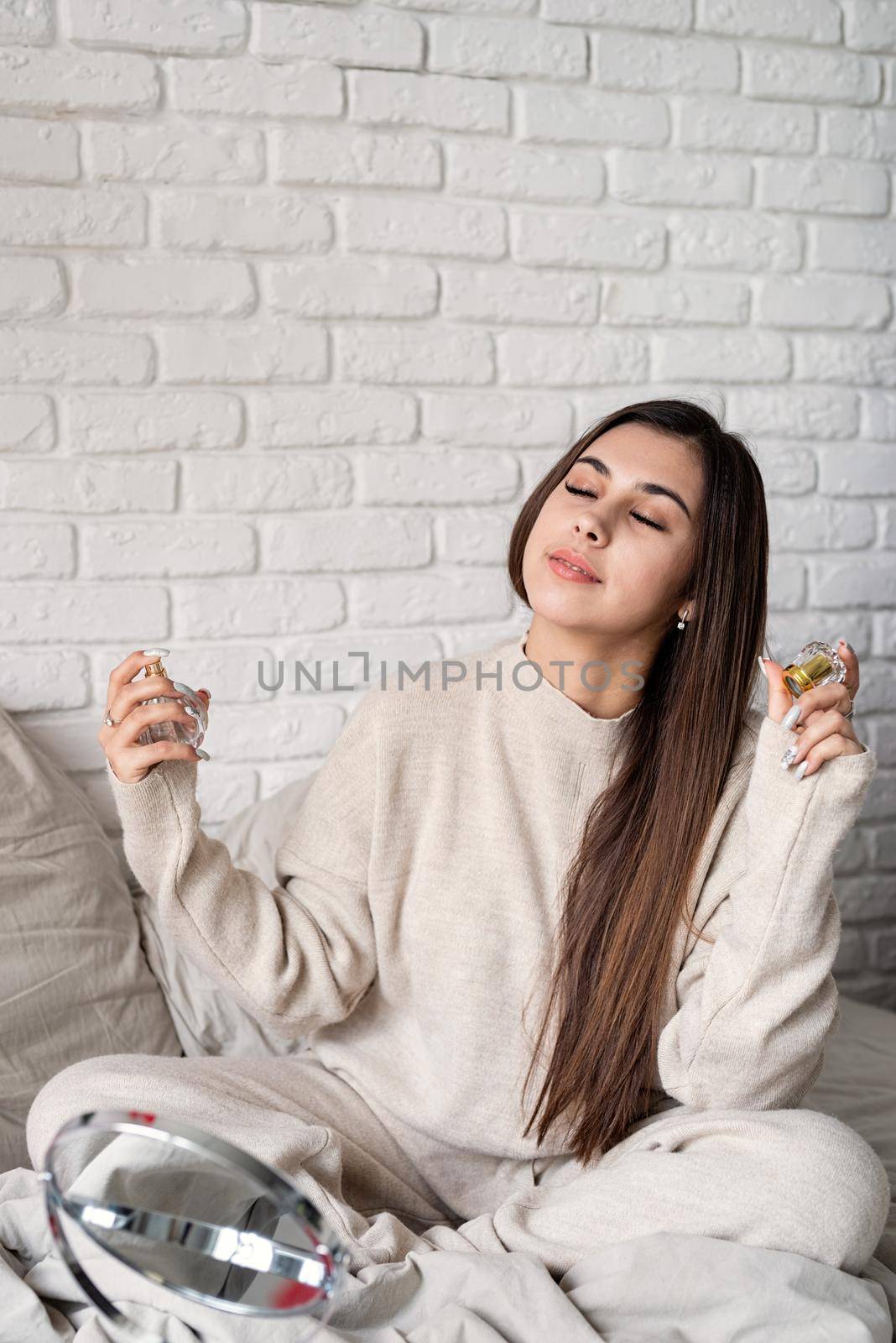 Valentine's day, Women's day. Brunette young caucasian Woman sitting on the bed making up applying perfume