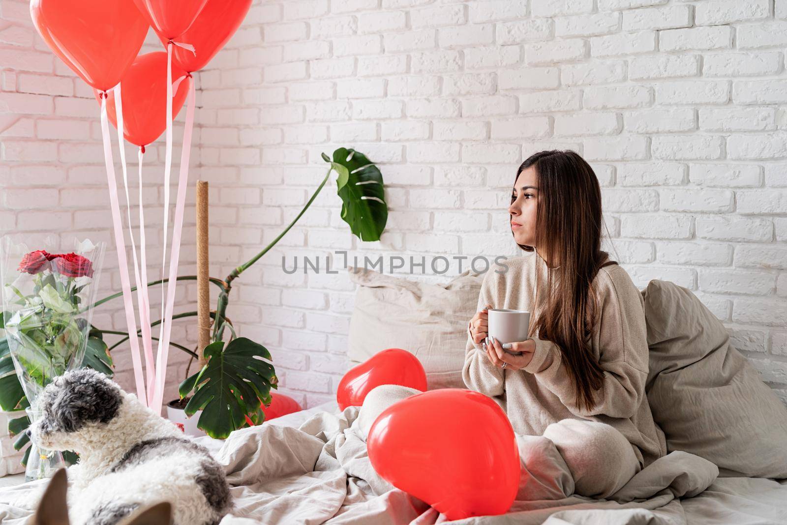 Young brunette woman sitting in the bed celebrating valentine day holding cup of coffee by Desperada