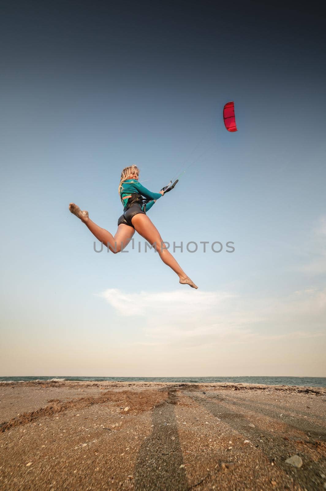 Sportswoman kitesurfer jumps with her kite on the beach. Free flight over land with a kite.
