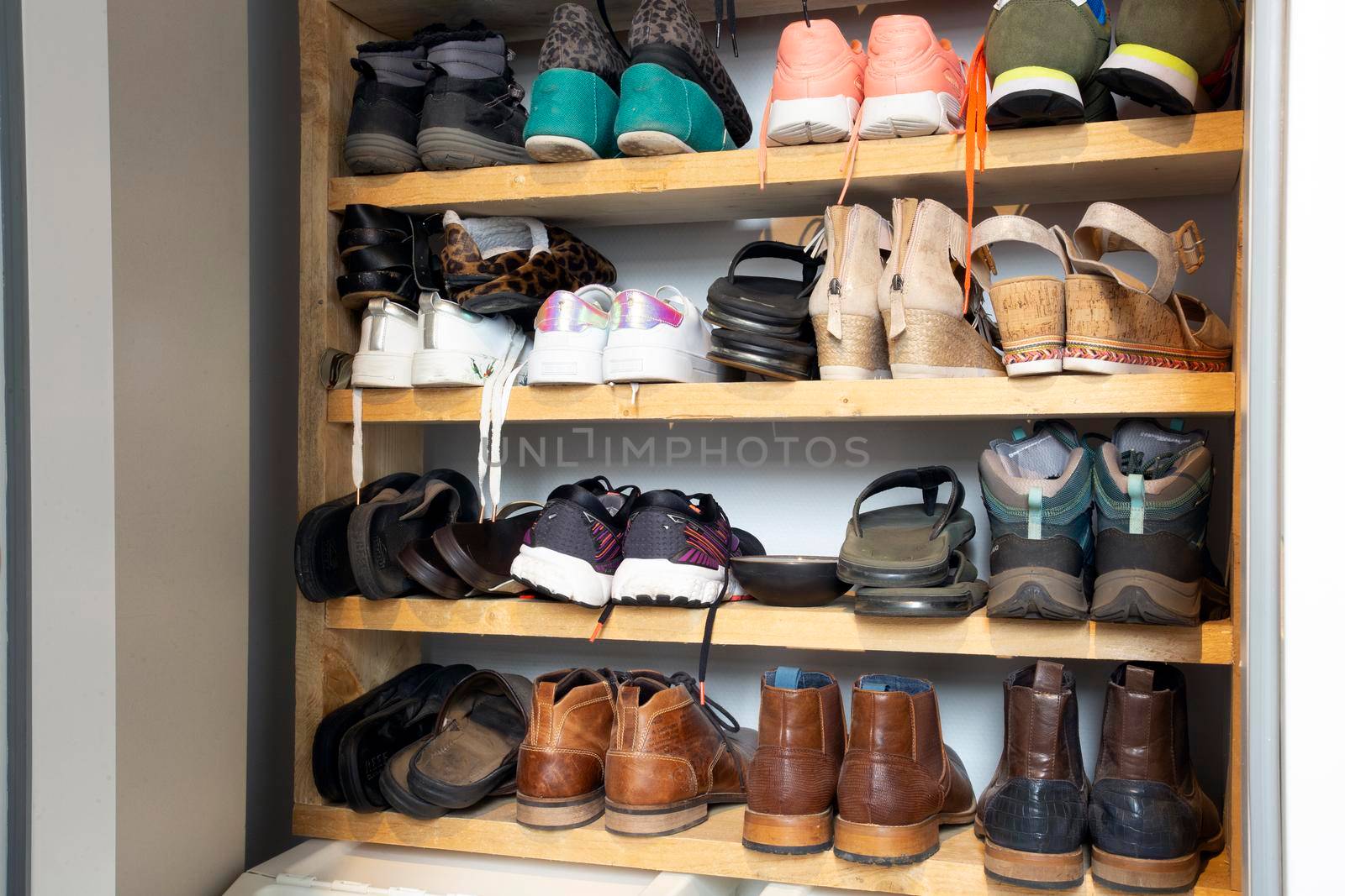 Collection of different shoes in shoe rack for storage, messy and needs organize, wardrobe with shelfs in house interior design stylish decoration close up