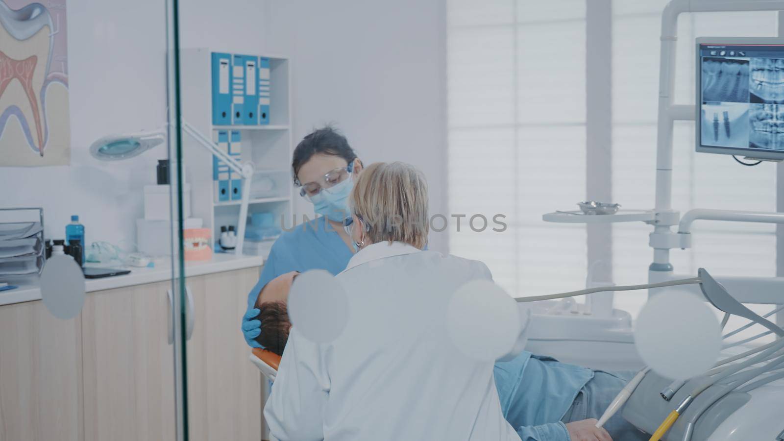 Nurse and stomatologist using drill tool to remove caries in dentistry cabinet. Team of specialists performing surgical procedure on patient to cure cavity problems and toothache.