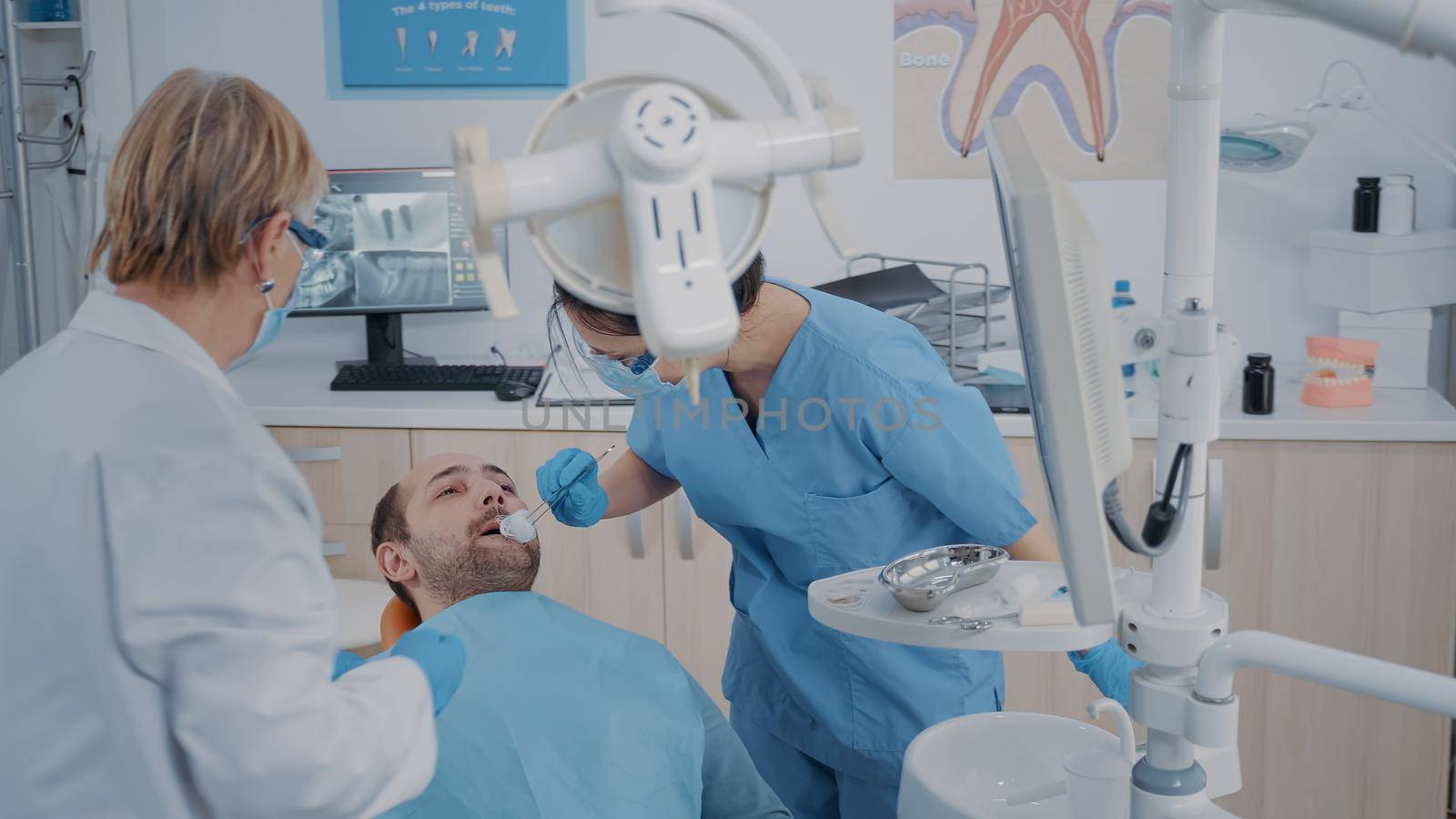 Dentistry team performing tooth extraction in stomatology cabinet, doing orthodontic procedure on patient in pain. Nurse and dentist using dental tools and equipment for oral care.