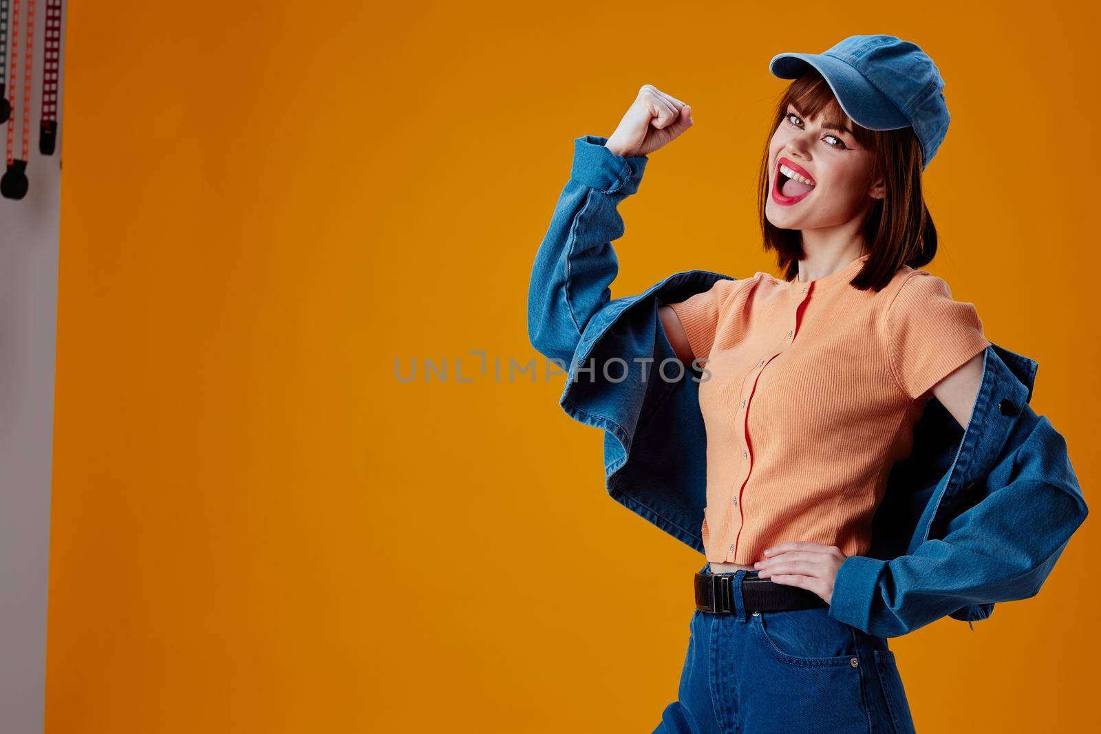 Pretty young female in a cap and denim jacket posing color background unaltered by SHOTPRIME